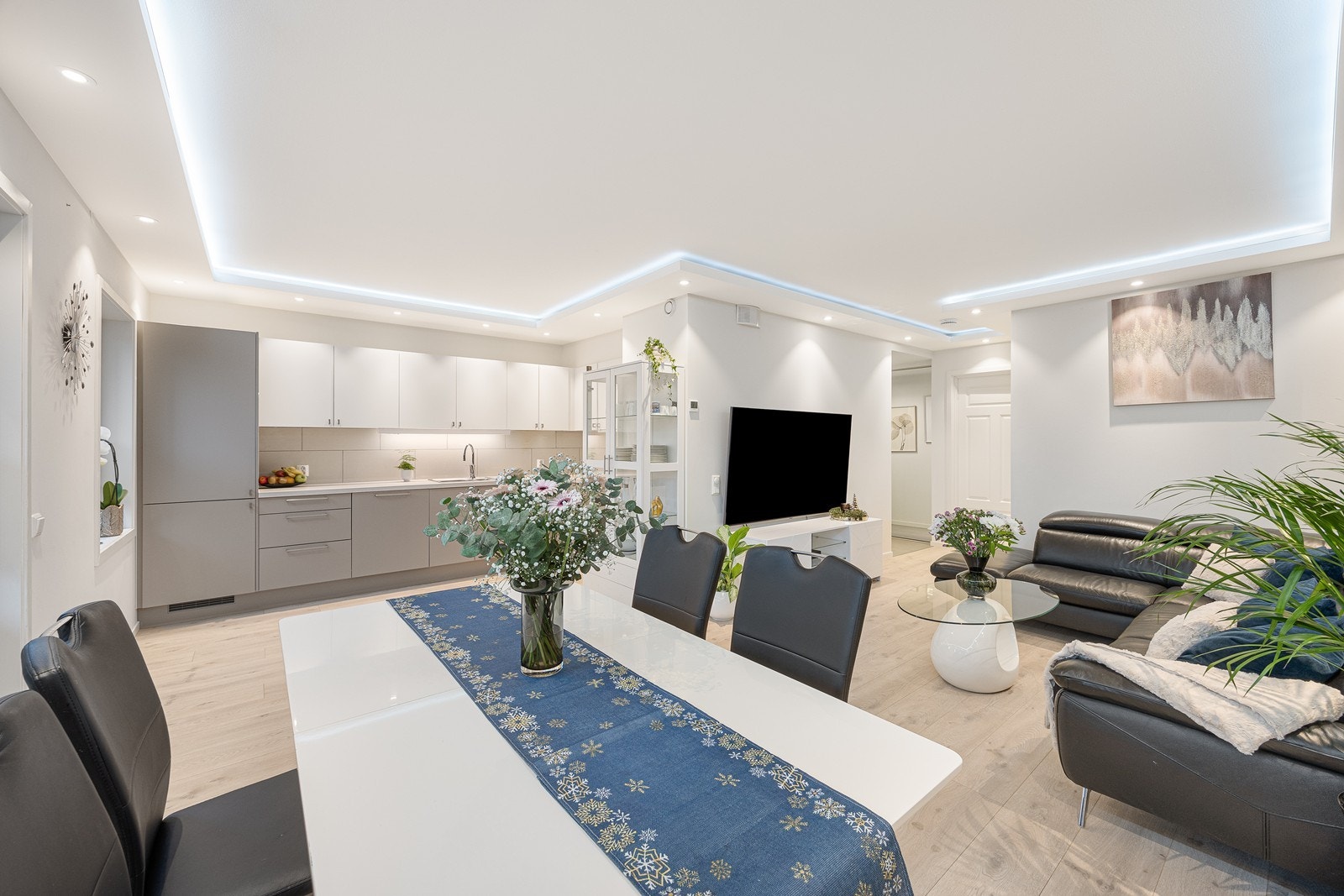 Stuen og kjøkkenet ligger i åpen løsning, og sammen danner de et stort, innbydende allrom med luftig atmosfære og stilfull designbelysning Galleribilde