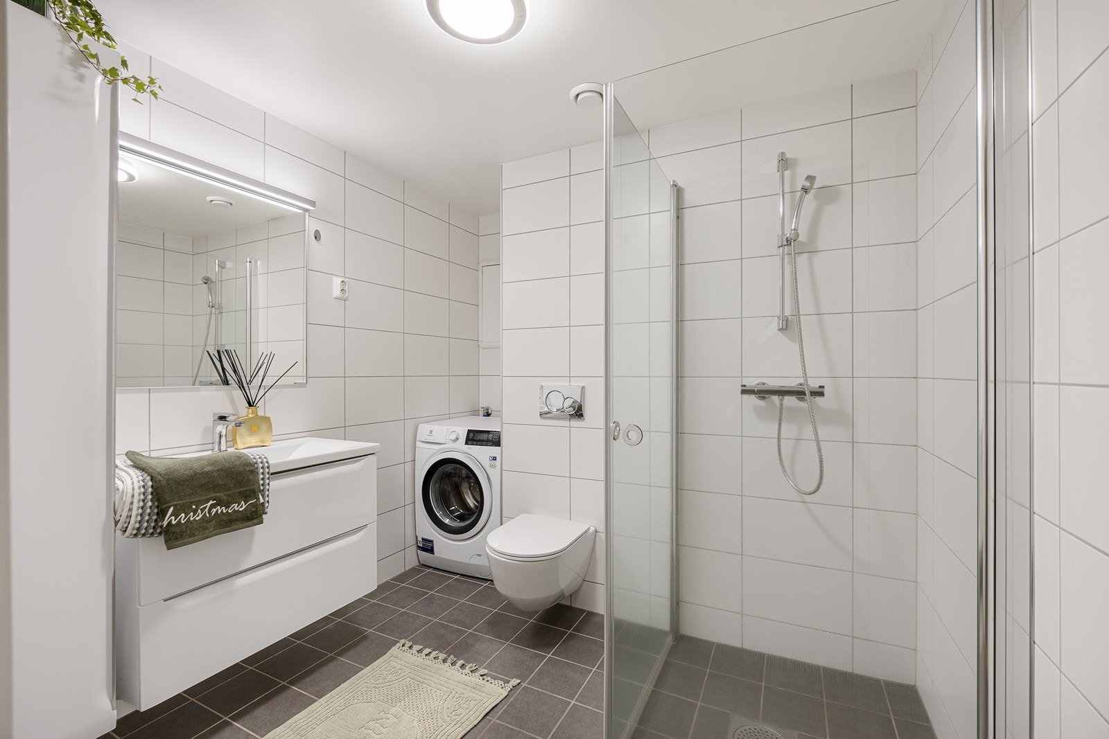 Leiligheten har et moderne og delikat bad med hvite fliser på veggene og grå fliser på gulv med vannbåren gulvvarme Galleribilde