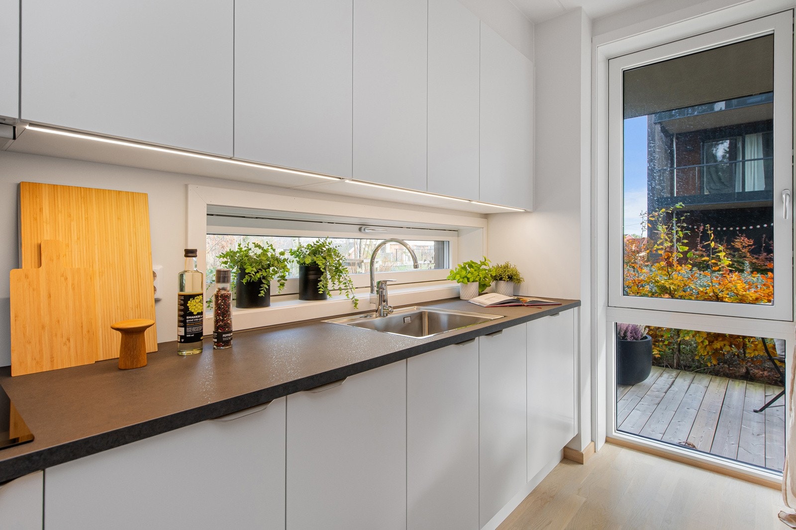 Hyggelig vindu på kjøkkenet mellom benk og overskap Galleribilde