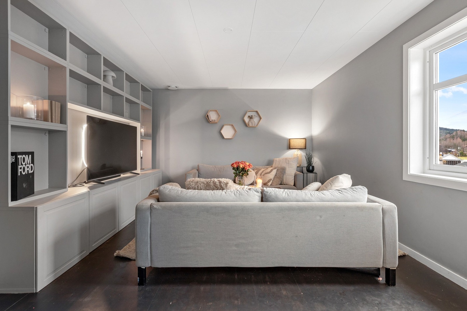 Stuen er et lunt og innbydende rom der lys grå vegger og store vinduer skaper en behagelig atmosfære. Galleribilde