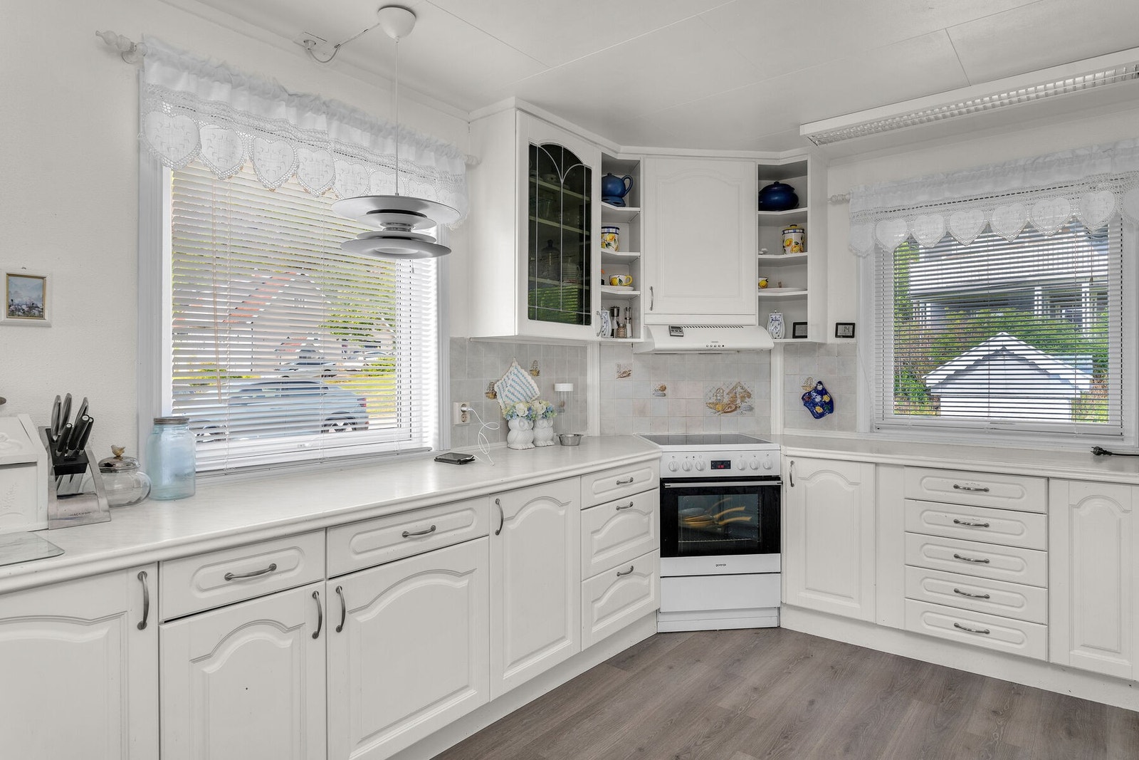 Tidløst kjøkken med lyse, profilerte fronter og opplegg for frittstående hvitevarer. Galleribilde