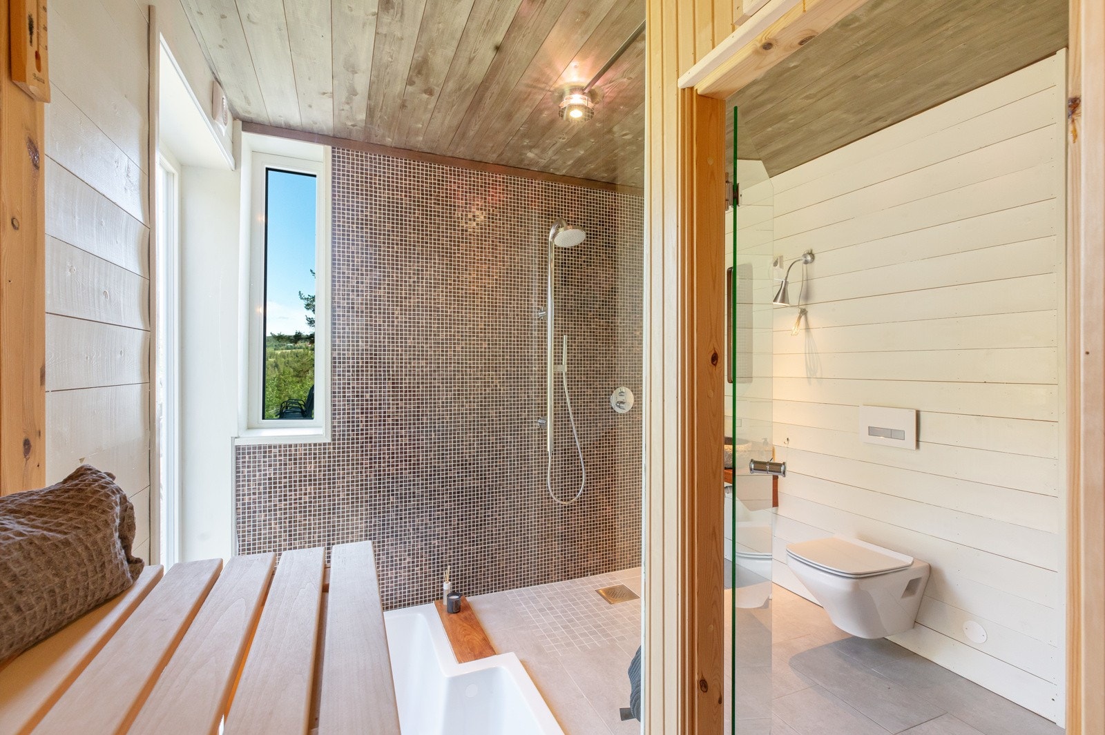 Badet har dusj, badekar, toalett og benk med stilig valg av servant Galleribilde