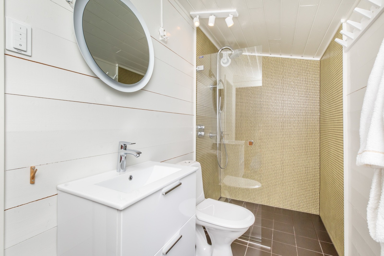 Dette badet har mosaikkfliser i dusjnisje, toalett og innredning med underskuffer og nedfelt servant Galleribilde