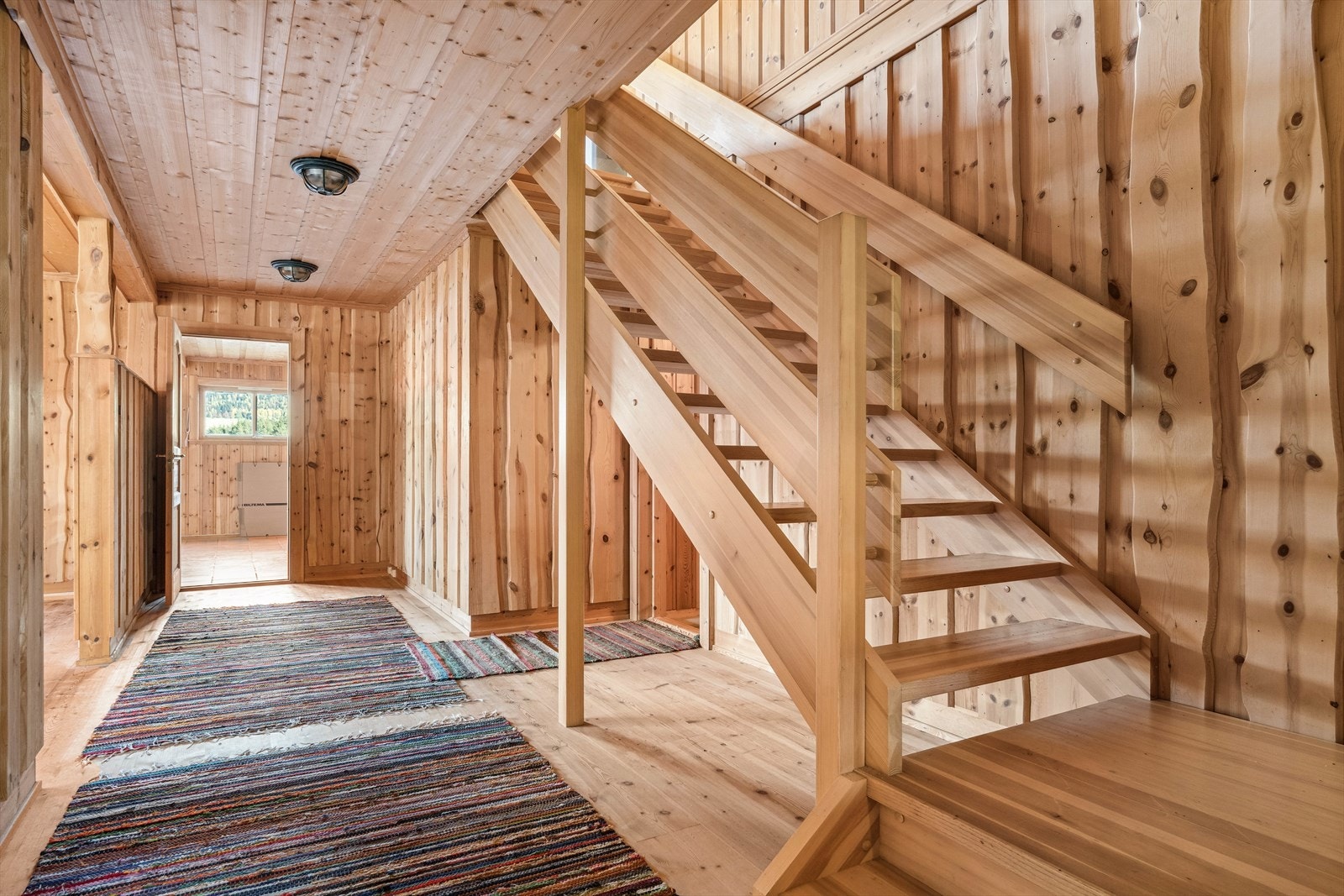 Fra det overbygde inngangspartiet kommer en inn i liten entré og en større gang med plass til yttertøy og sko. Fra gangen går det trapp opp i 2. etasje. Galleribilde