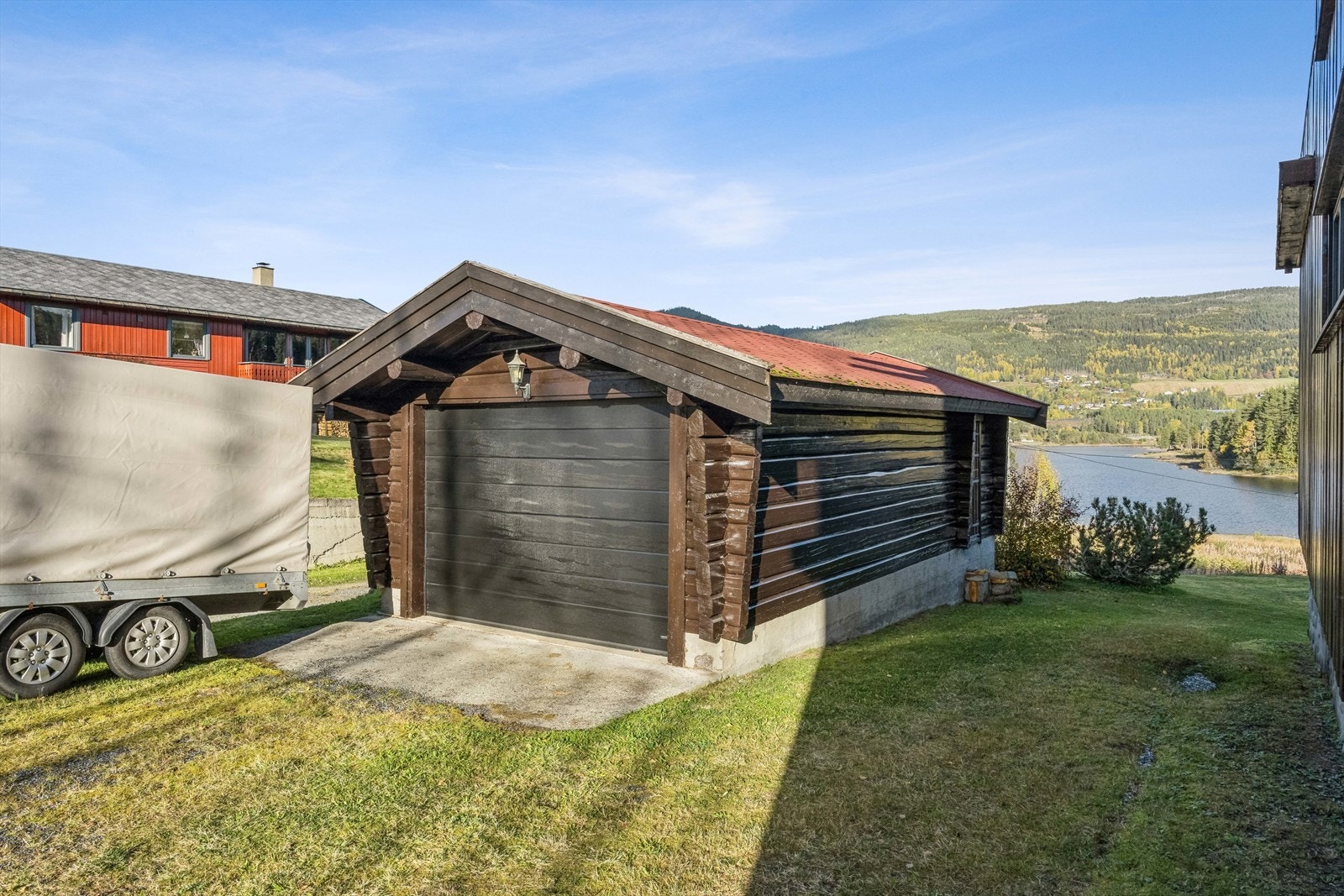 Garasjen har støpt plate av betong og elektrisk leddheisport. I bakkant er det en liten bod, praktisk til oppbevaring av verktøy og tørr ved. Galleribilde