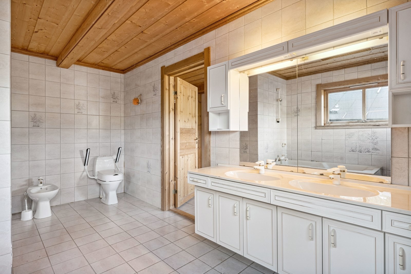 Hovedbadet ligger praktisk plassert og med lett tilgjengelighet fra soverommet. Badet har nyere innredning med dobbel benkeservant, vegghengt speilskap, gulvstående toalett, bidé og badekar. Galleribilde