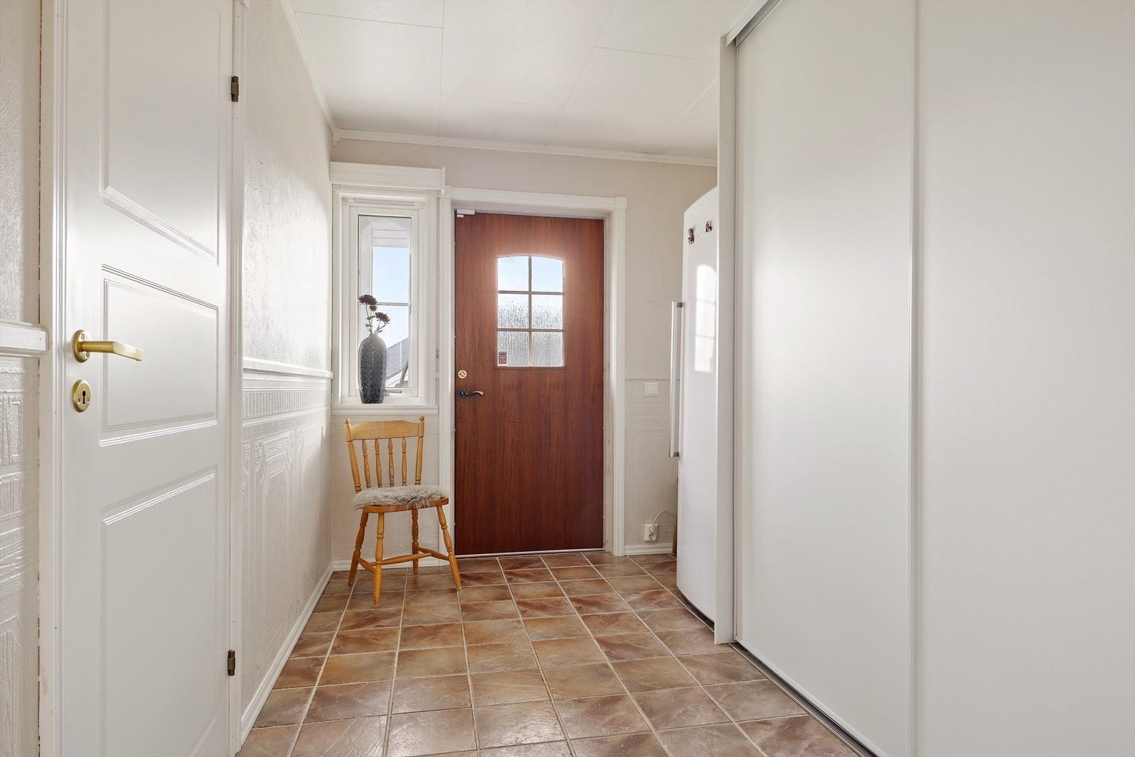 Velkommen inn i en romslig og flislagt entré med praktisk skyvedørsgarderobe - en ryddig og funksjonell start på boligen. Galleribilde