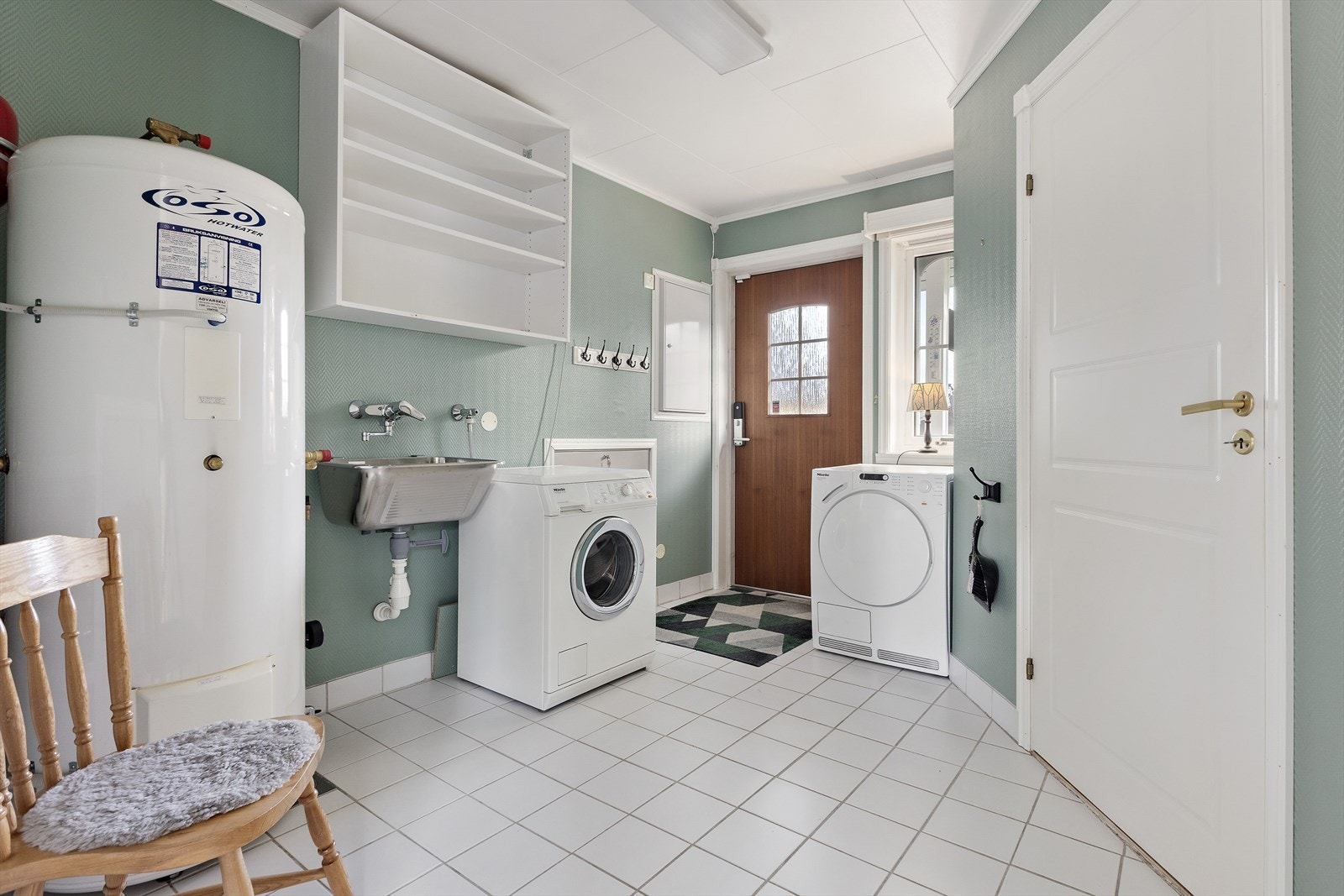 Stort vaskerom med egen utgang, utslagsvask, opplegg for vaskemaskin, plass til tørketrommel, VVB - en praktisk løsning som gjør klesvask og husarbeid enklere. Fra vaskerommet får du også adkomst til en bod. Galleribilde