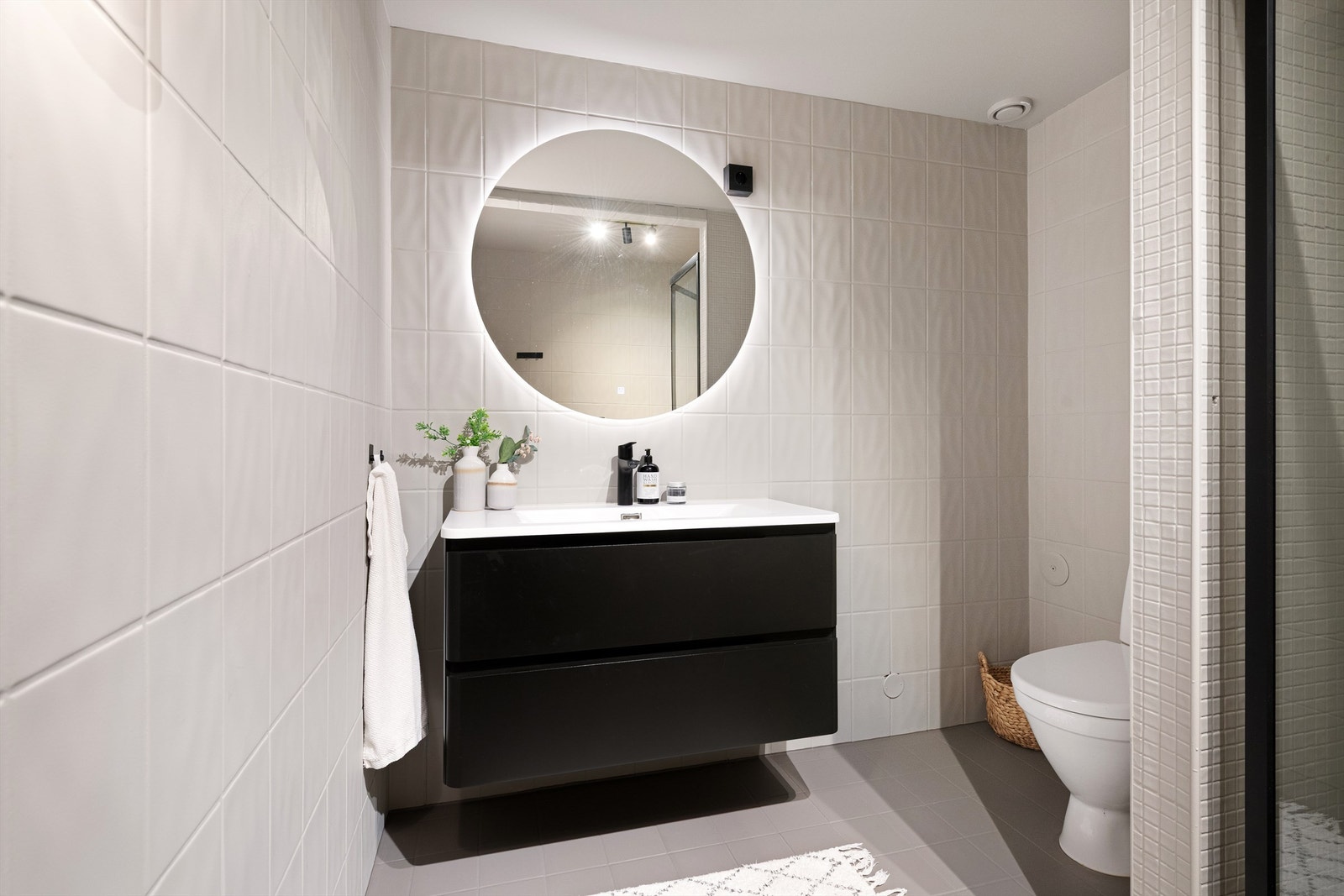 Baderomsinnredning med skuffer med sorte fronter og ovenpåliggende servant fra 2025 med sort ett-greps armatur. Gulstående toalett. Galleribilde