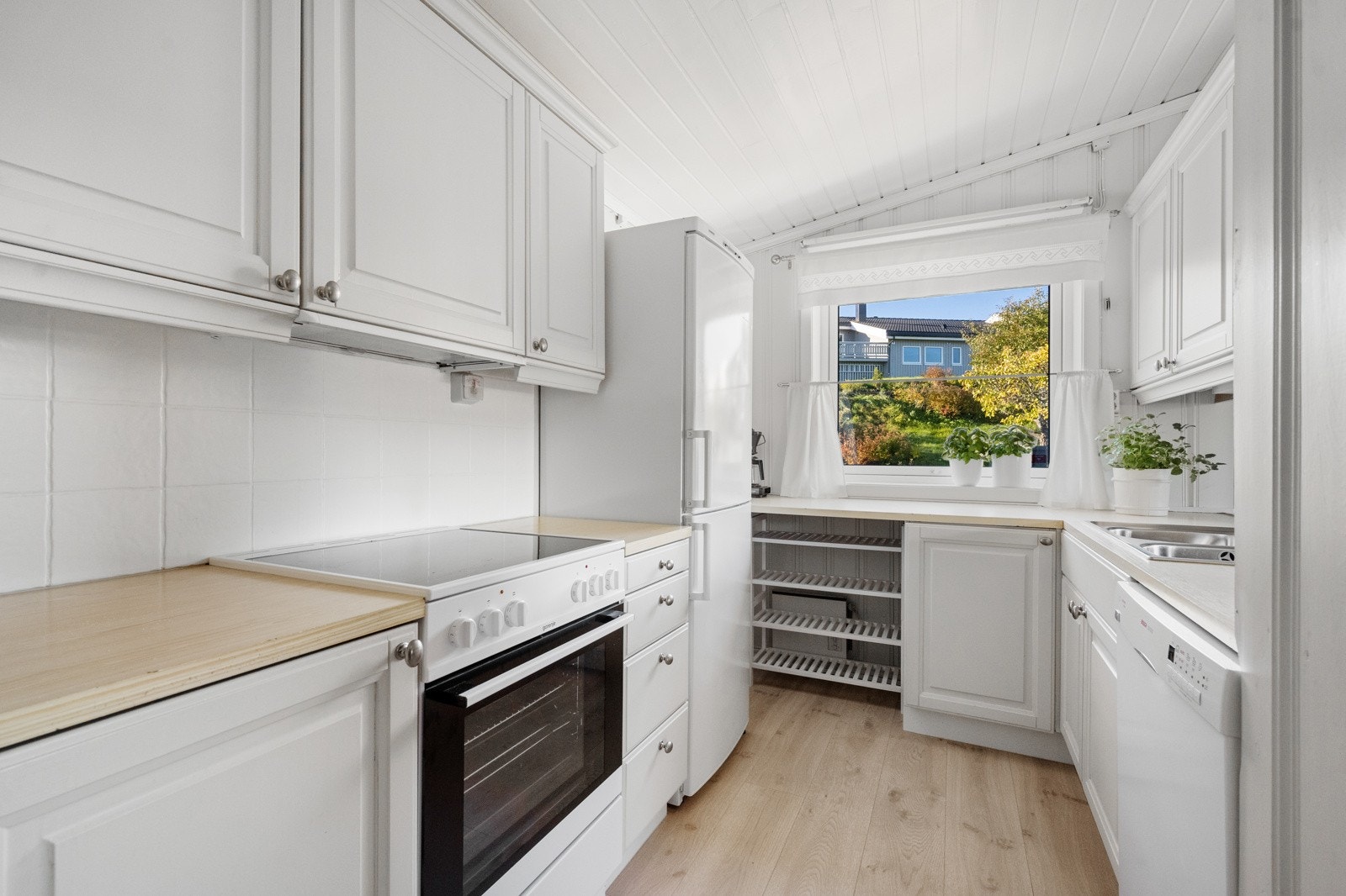 Kjøkkenet har profilerte fronter, flislagt vegg og plass til alle nødvendige hvitevarer. Galleribilde