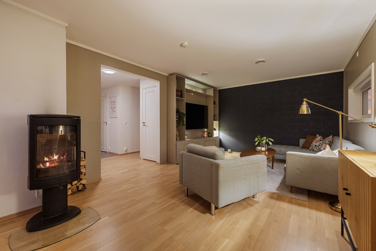 Midt i rommet står peisen, som gir varme til hele oppholdsarealet og samtidig fungerer som et elegant blikkfang. Galleribilde