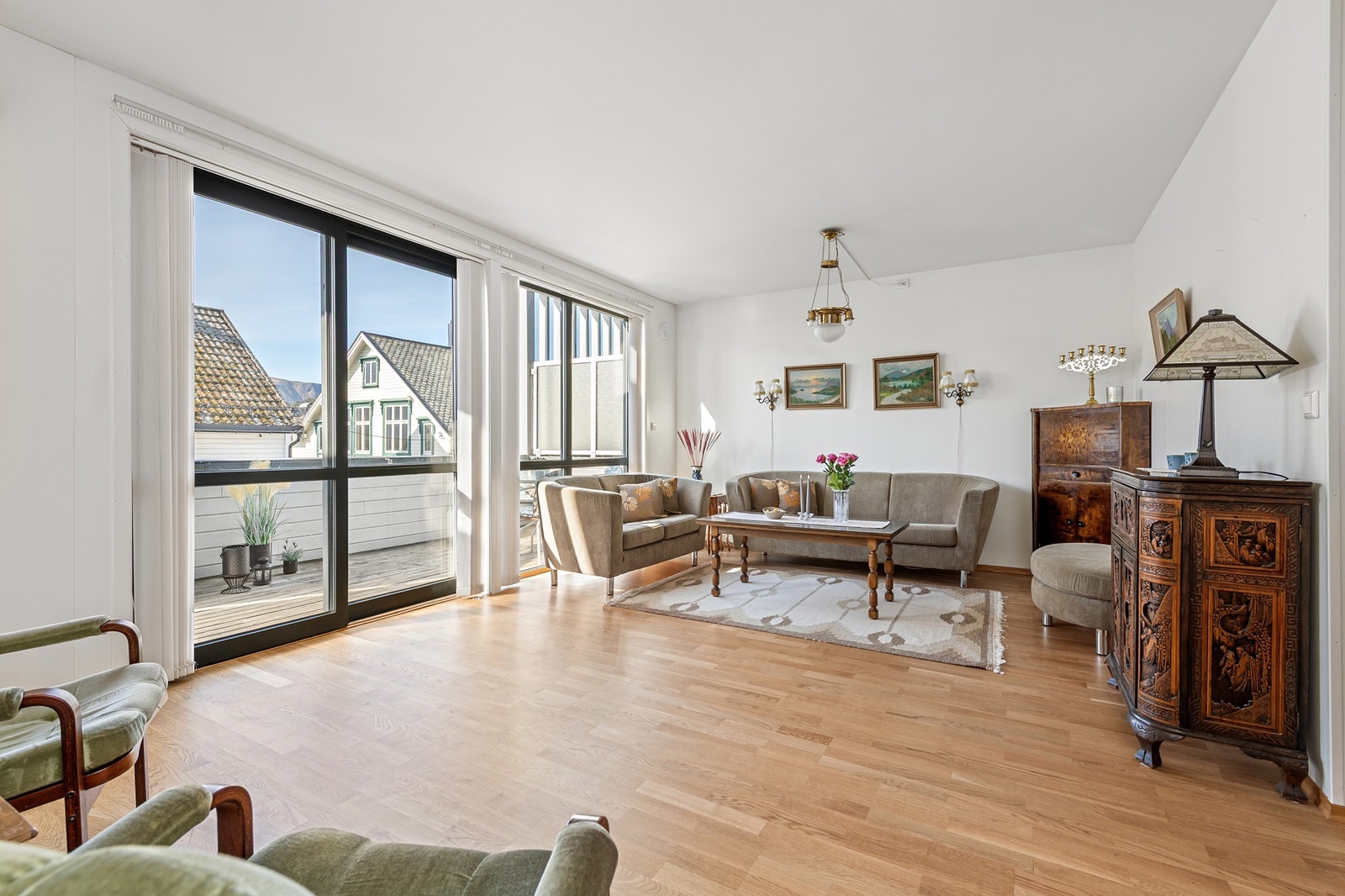 Lys og romslig stue med store vinduer og utgang til terrasse Galleribilde