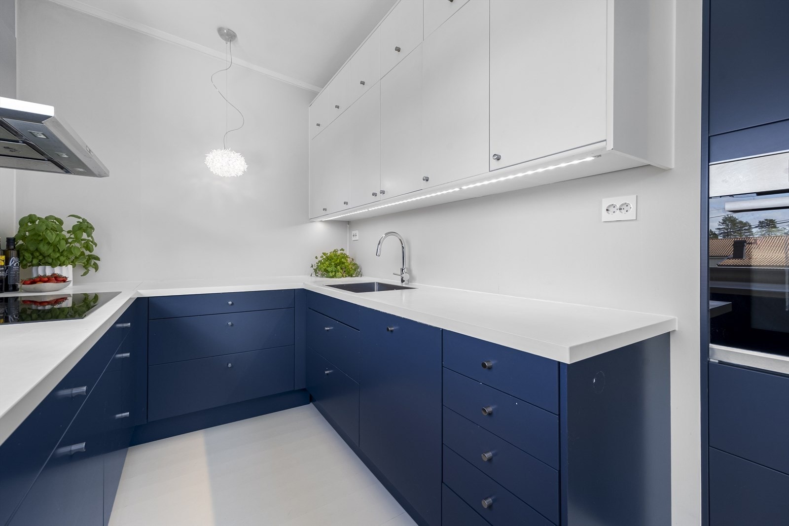 Innredning er i matchende hvit og blå design med laminat benkeplate og integrerte hvitevarer som inkluderer bred induksjonstopp, oppvaskmaskin og komfyr. Galleribilde