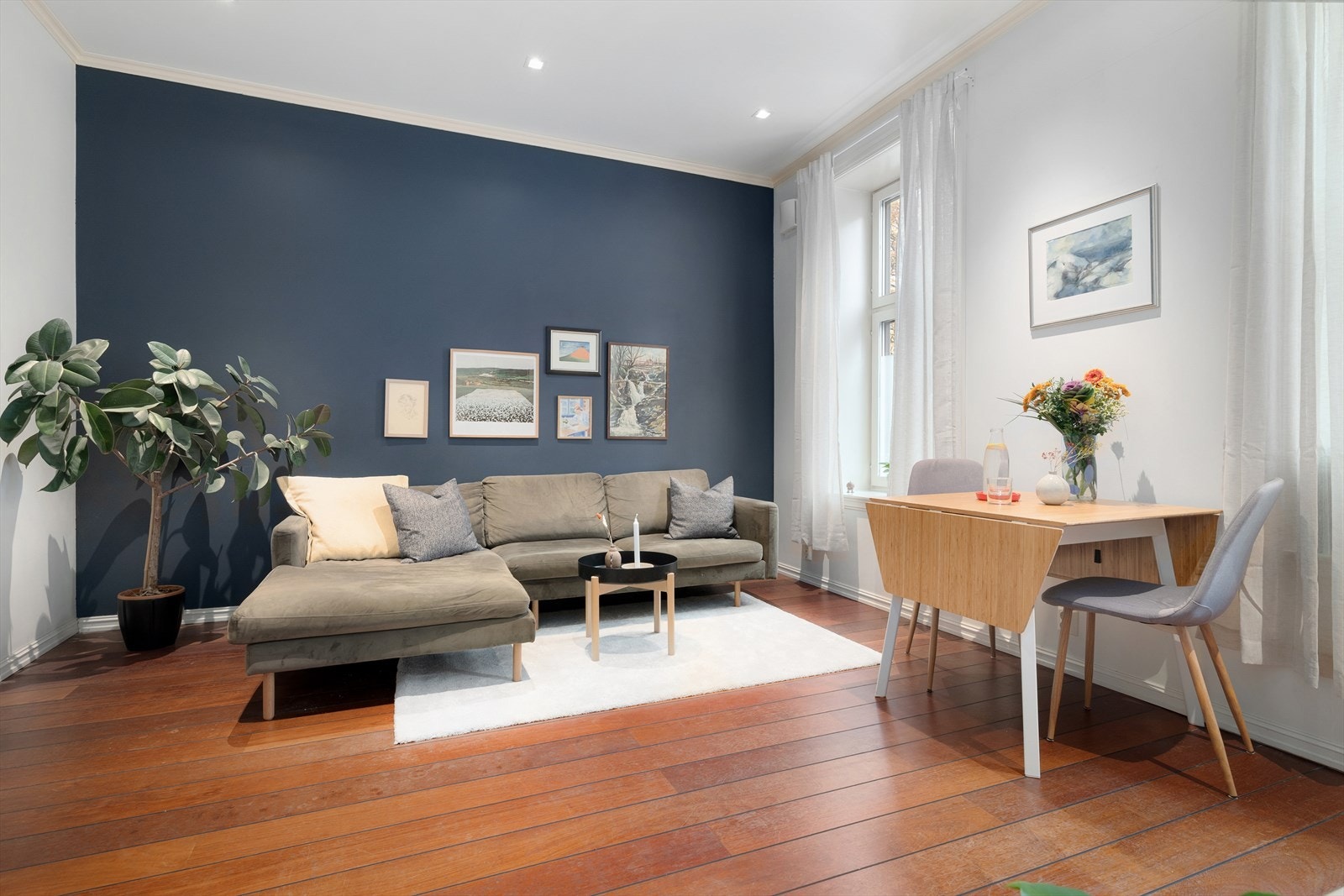 I den koselige stuen er det lett å føle seg hjemme. Det er varme i gulv noe som sørger for en behagelig innetemperatur uansett årstid. Den harmoniske blå kontrastveggen skaper en lun og god atmosfære. De store vinduene slipper godt med naturlig lys inn. Galleribilde