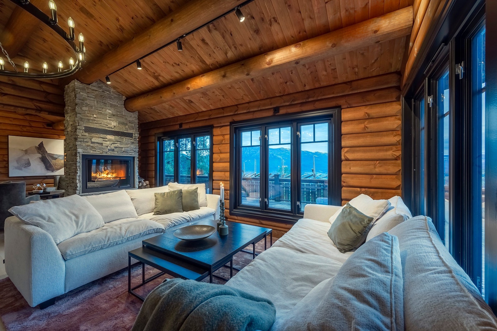 Stuen og kjøkkenet er over 50kvm men fremstår samtidig intim hvor tømmerveggene og peisen med innsyn fra 2-sider skaper den autentiske hyttefølelsen. Galleribilde