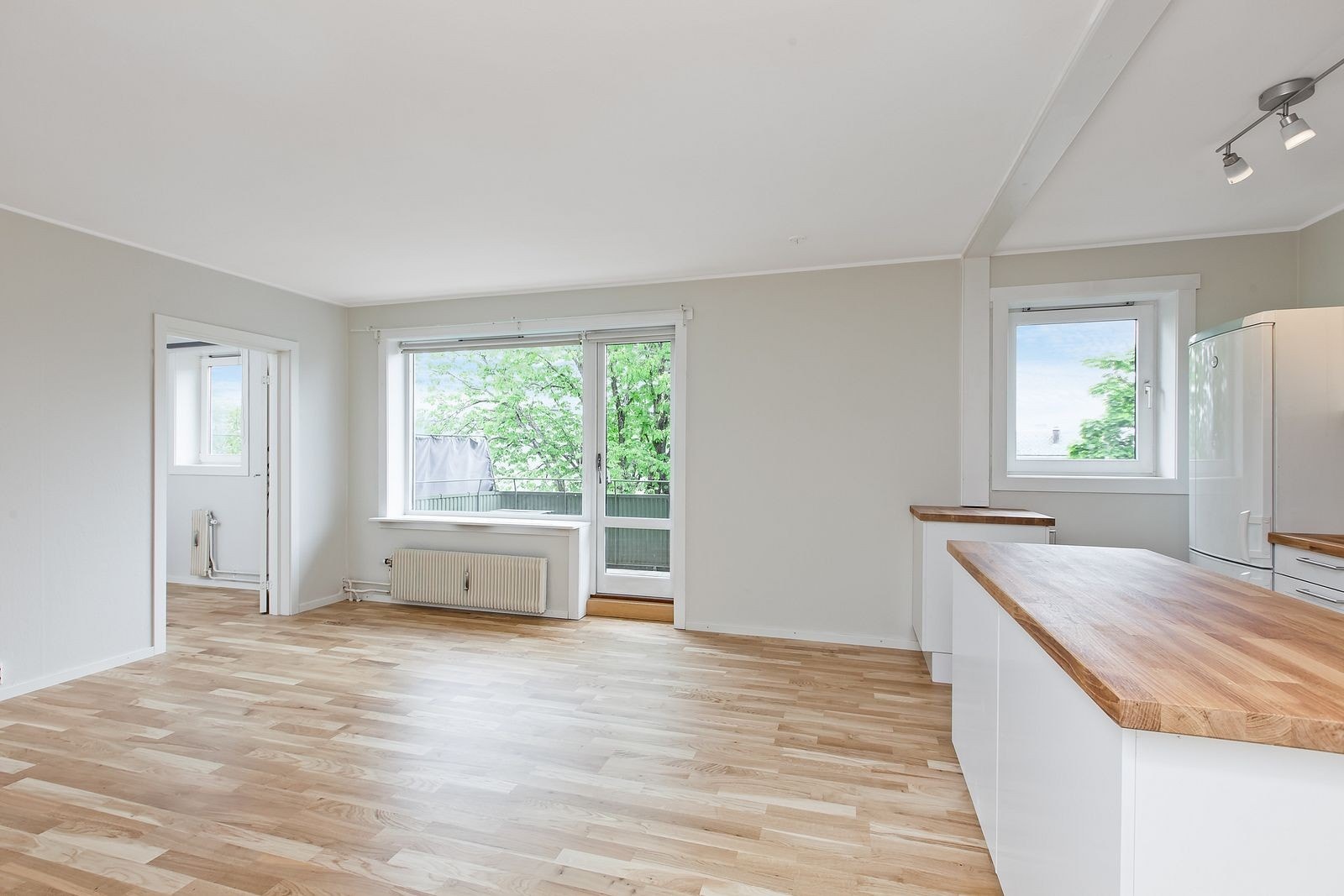 Nyoppusset stue (2023) med åpen kjøkkenløsning og utgang balkong. Leiligheten vender ut mot bakgård. Galleribilde