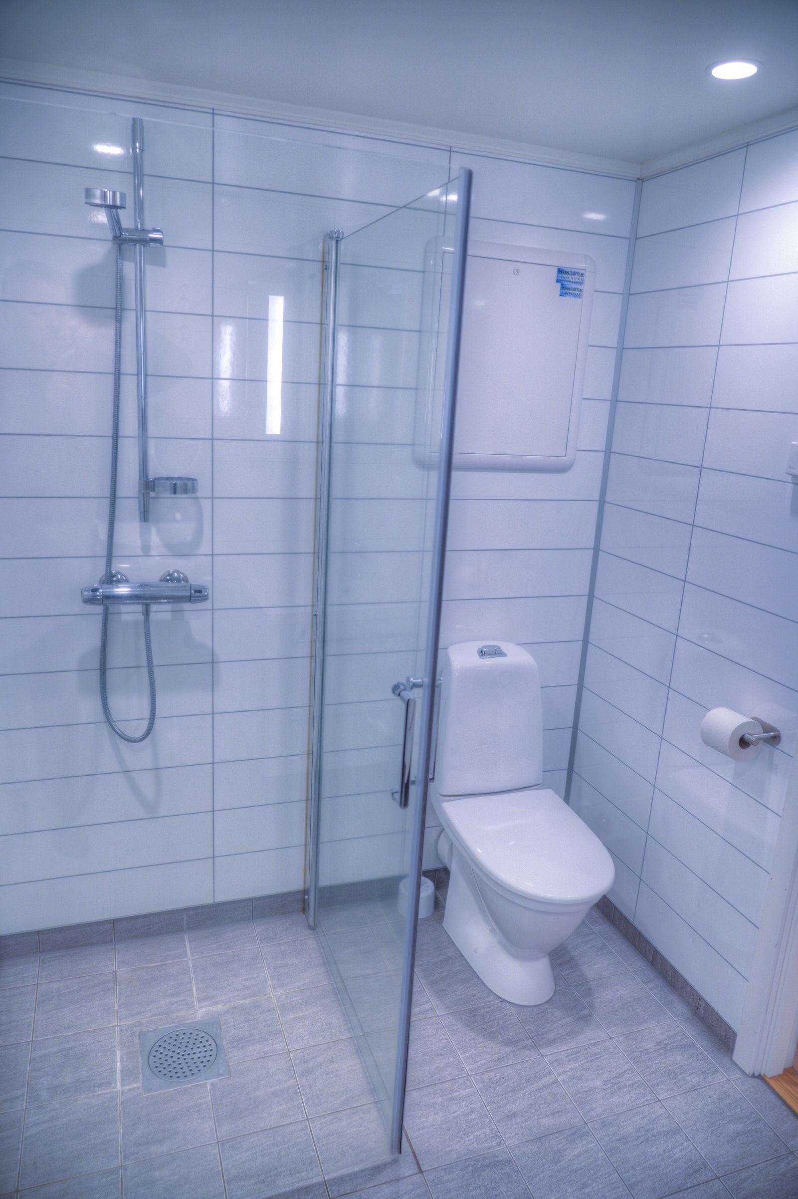 Moderne bad med dusjvegger, fliser på gulv og våtromsplater på vegger. Galleribilde