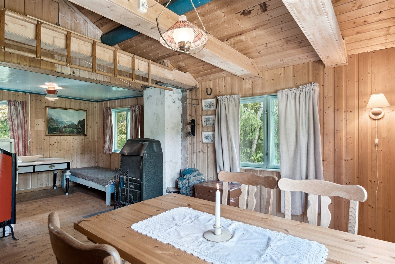 I delvis åpen løsning til stua er det innredet et rom med seng, bord, kjøleskap og microbølgeovn. Galleribilde