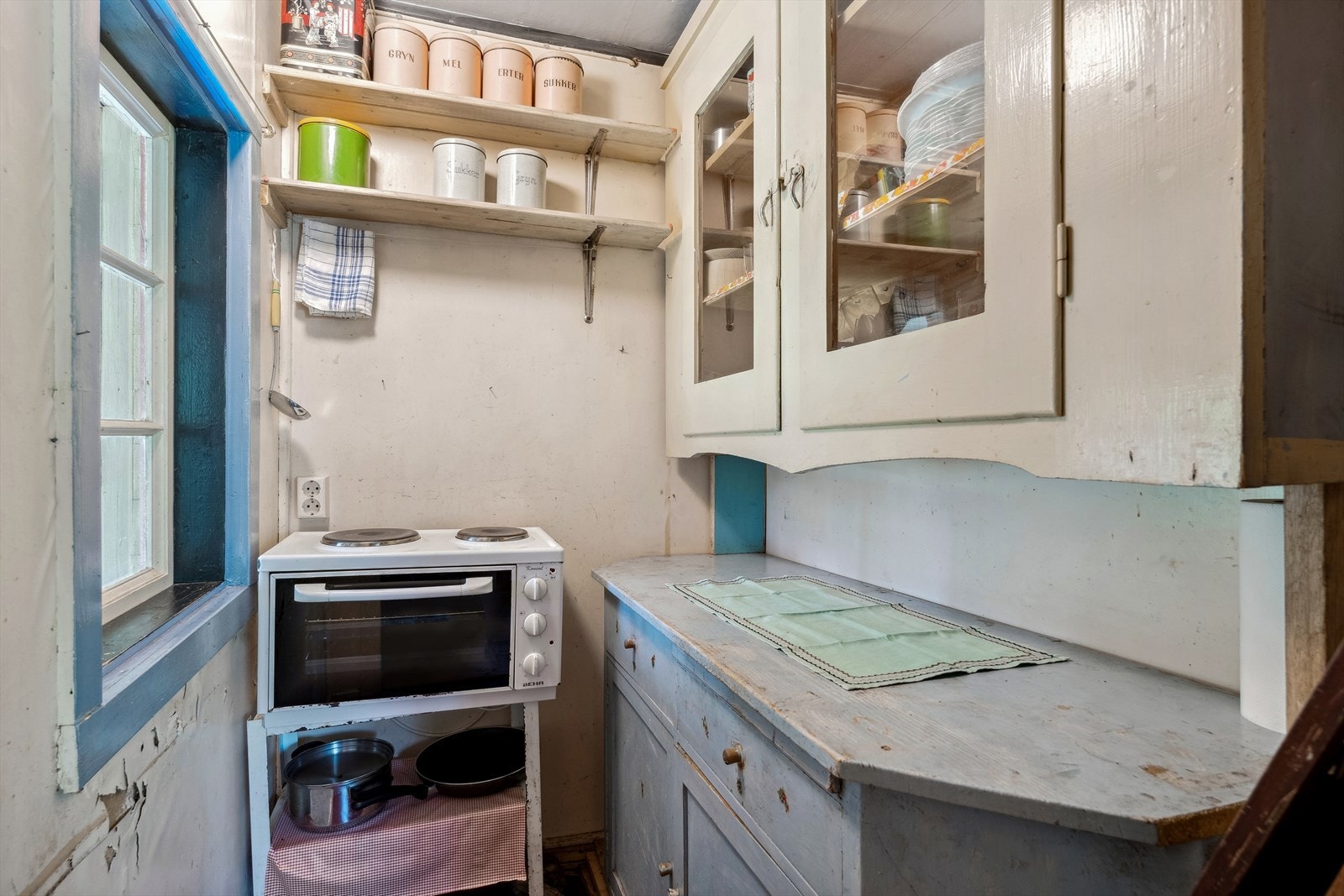 Kjøkkenet har enkel innredning med benkeplate og eldre over- og underskap i malt treverk. Galleribilde