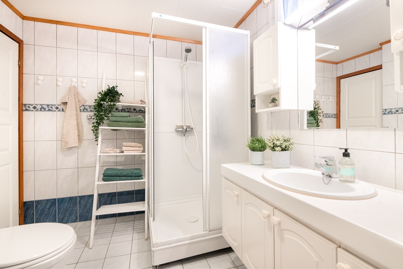 I underetasjen ligger bad/ vaskerommet med flis på gulv med varmekabler, flis på vegg og himlingsplater. Galleribilde