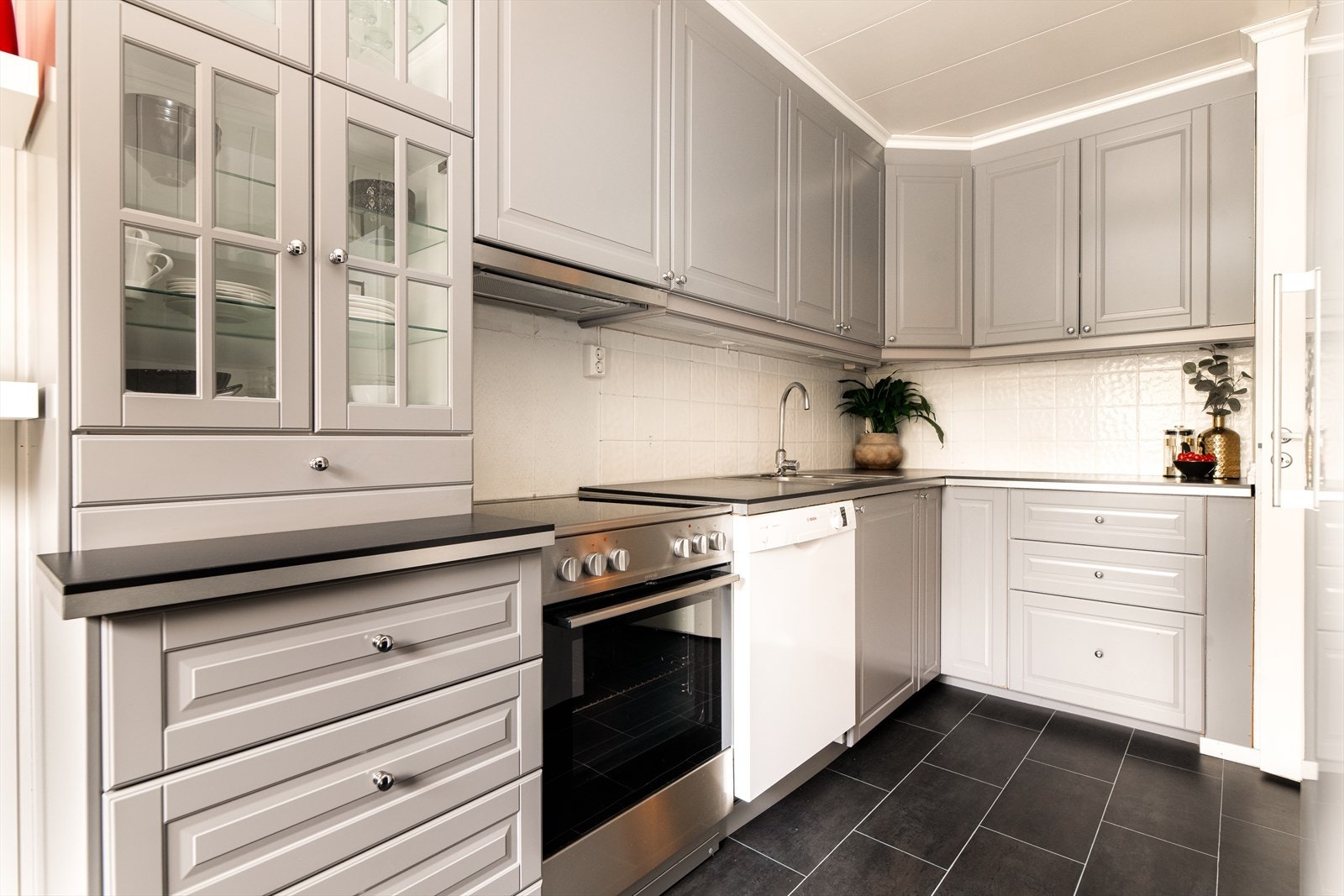 Pent kjøkken med lys grå innredning og profilerte fronter med laminert benkeplate og nedfelt vask. Galleribilde