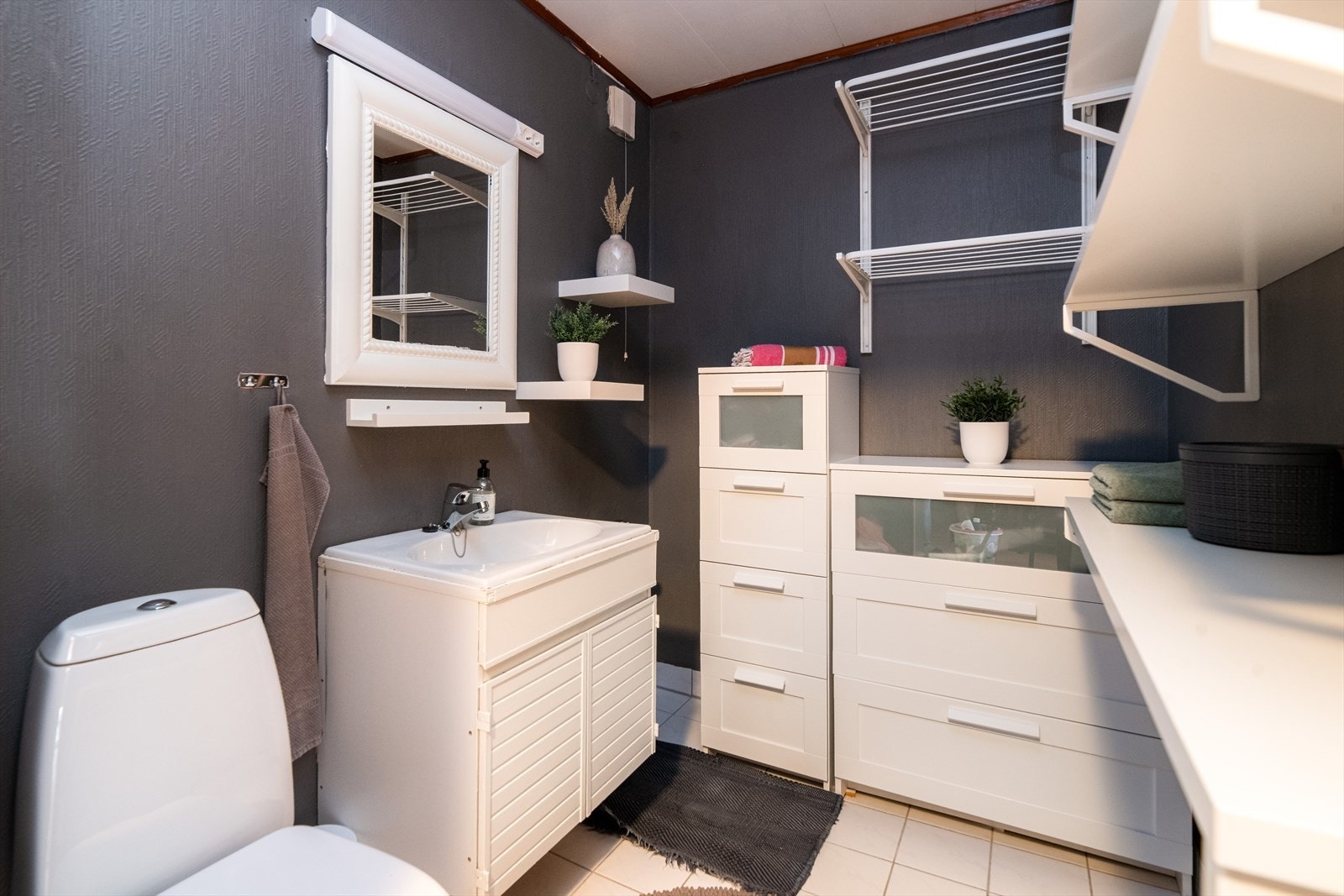 Toalettrommet ligger vegg i vegg med badet i underetasjen og inneholder gulvmontert toalett, servant med underskap og speil med lys over. På toalettrommet er det opplegg til badekar. Galleribilde