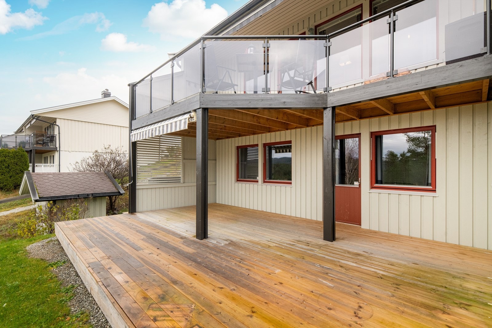 Terrassen er delvis overbygget fra overliggende veranda og ligget skjermet til med delvis levegg på sidene og manuell markise for solskjerming. Galleribilde