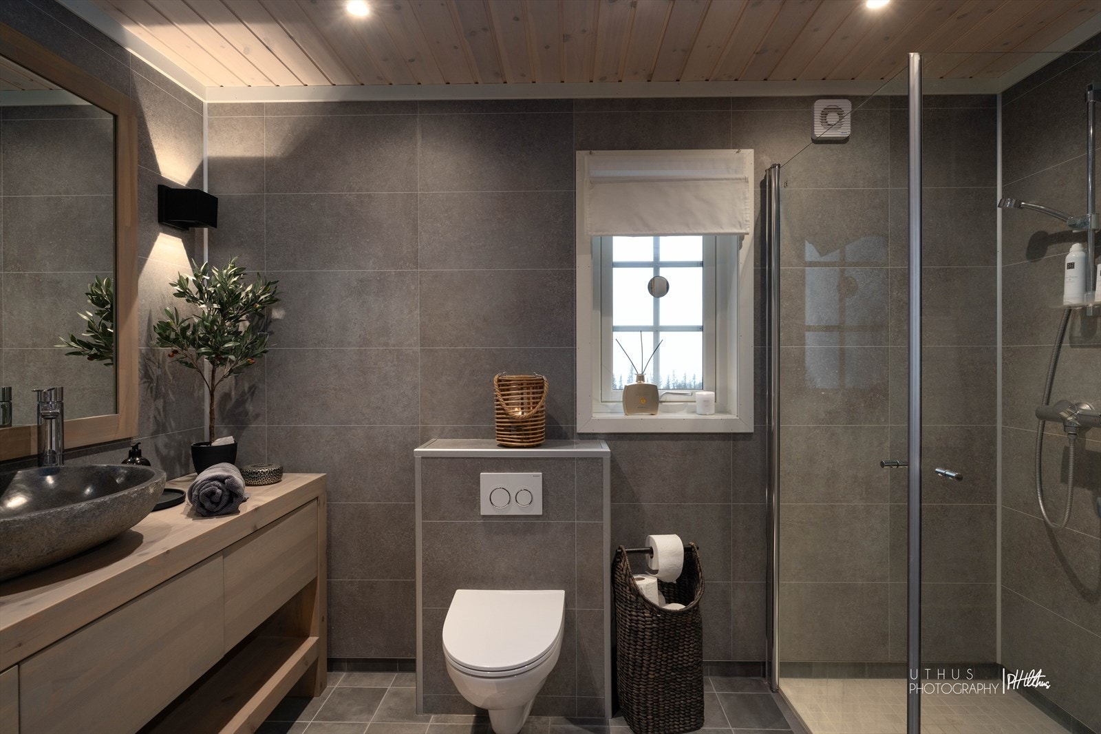 Vegghengt toalett, elektriske varmekabler og ventilasjon via avtrekksventil koblet til balansert ventilasjon. Mosaikk i dusjsonen gir et pent helhetsinntrykk. Galleribilde