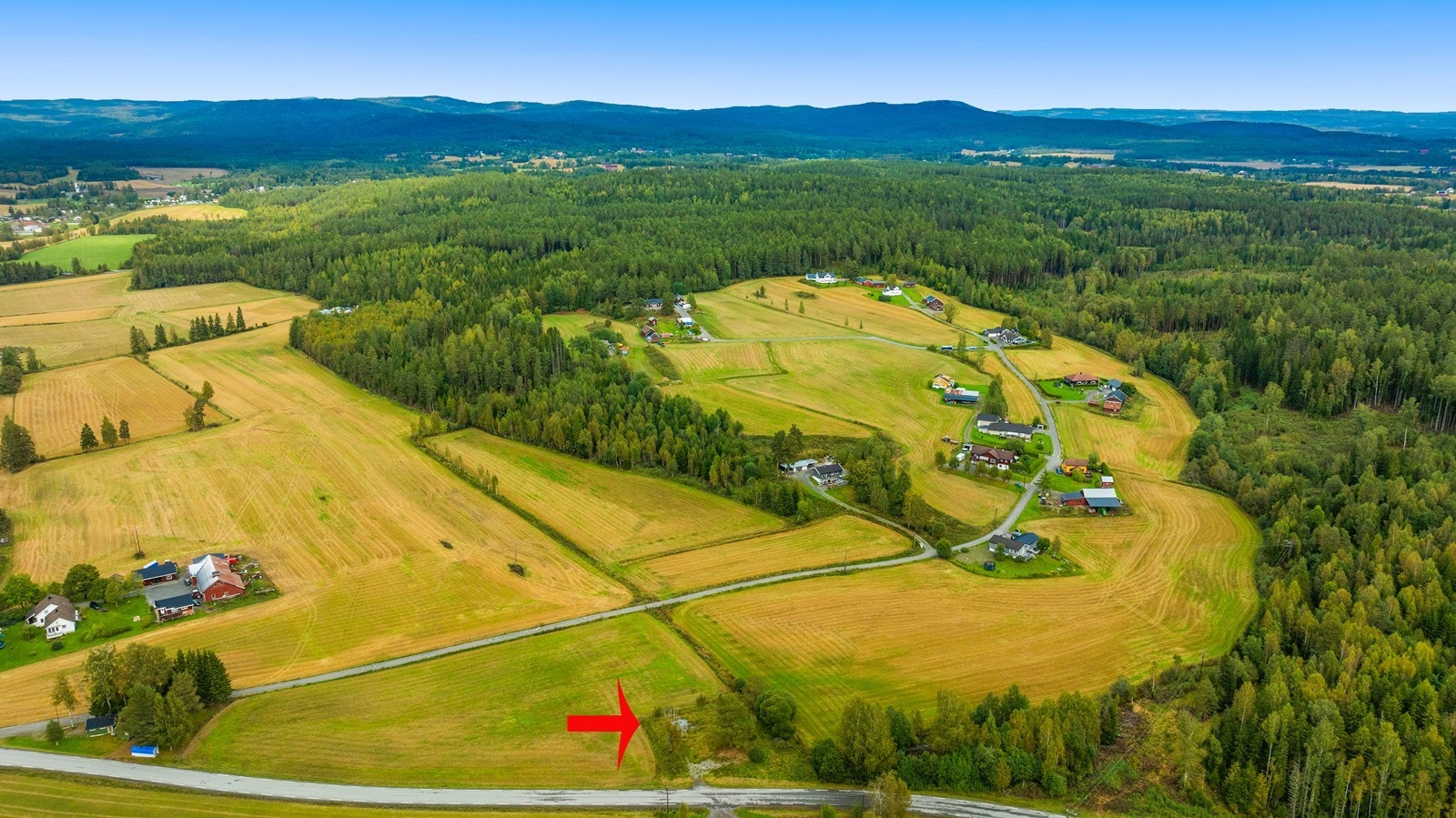 Her vises tomtens beliggenhet i det større landskapsbildet, omkranset av jorder og skog. Galleribilde