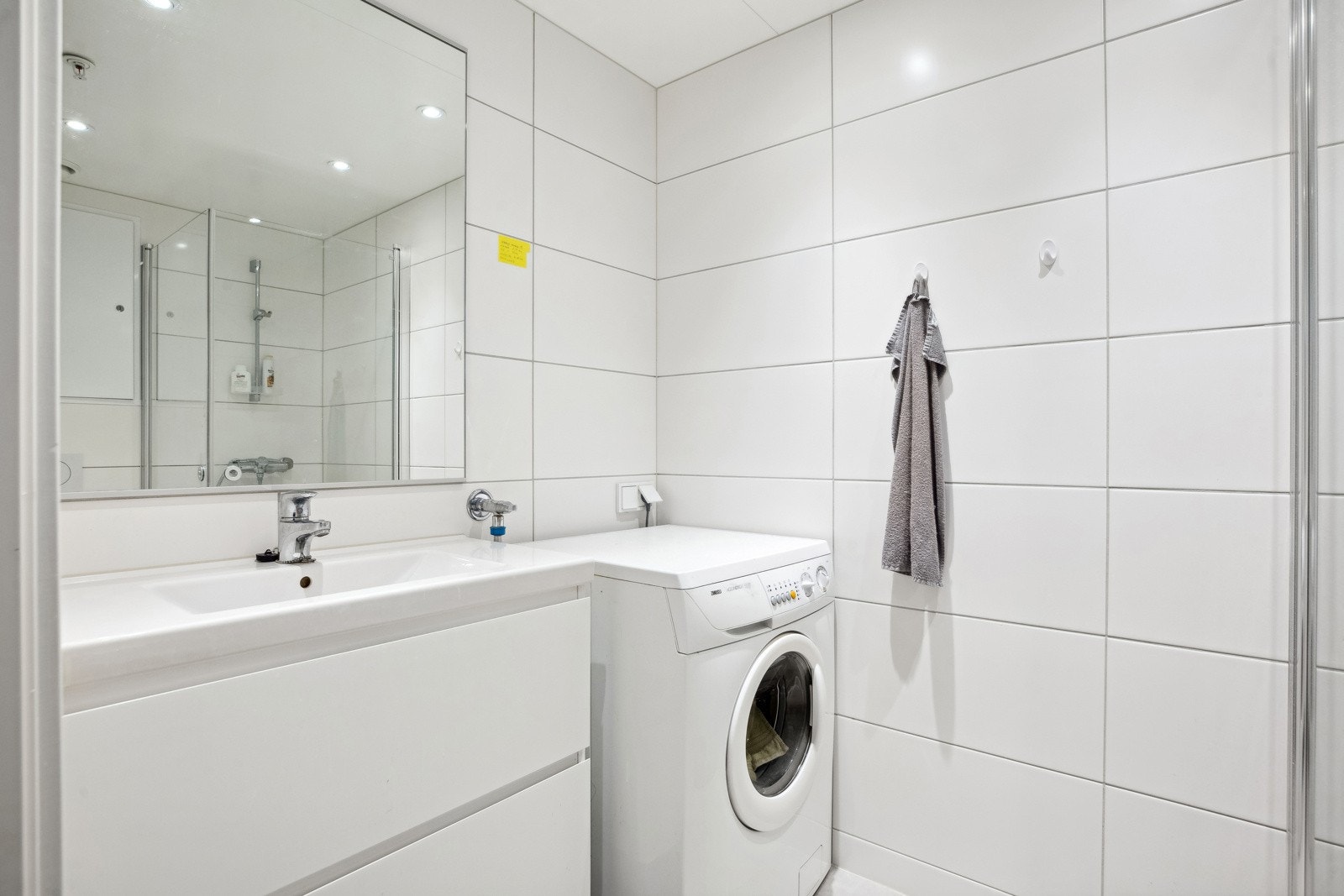 Badet er praktisk innredet med servant med store oppbevaringsskuffer i underkant, innfellbart dusjhjørne, vegghengt klosett og vaskemaskin. Galleribilde