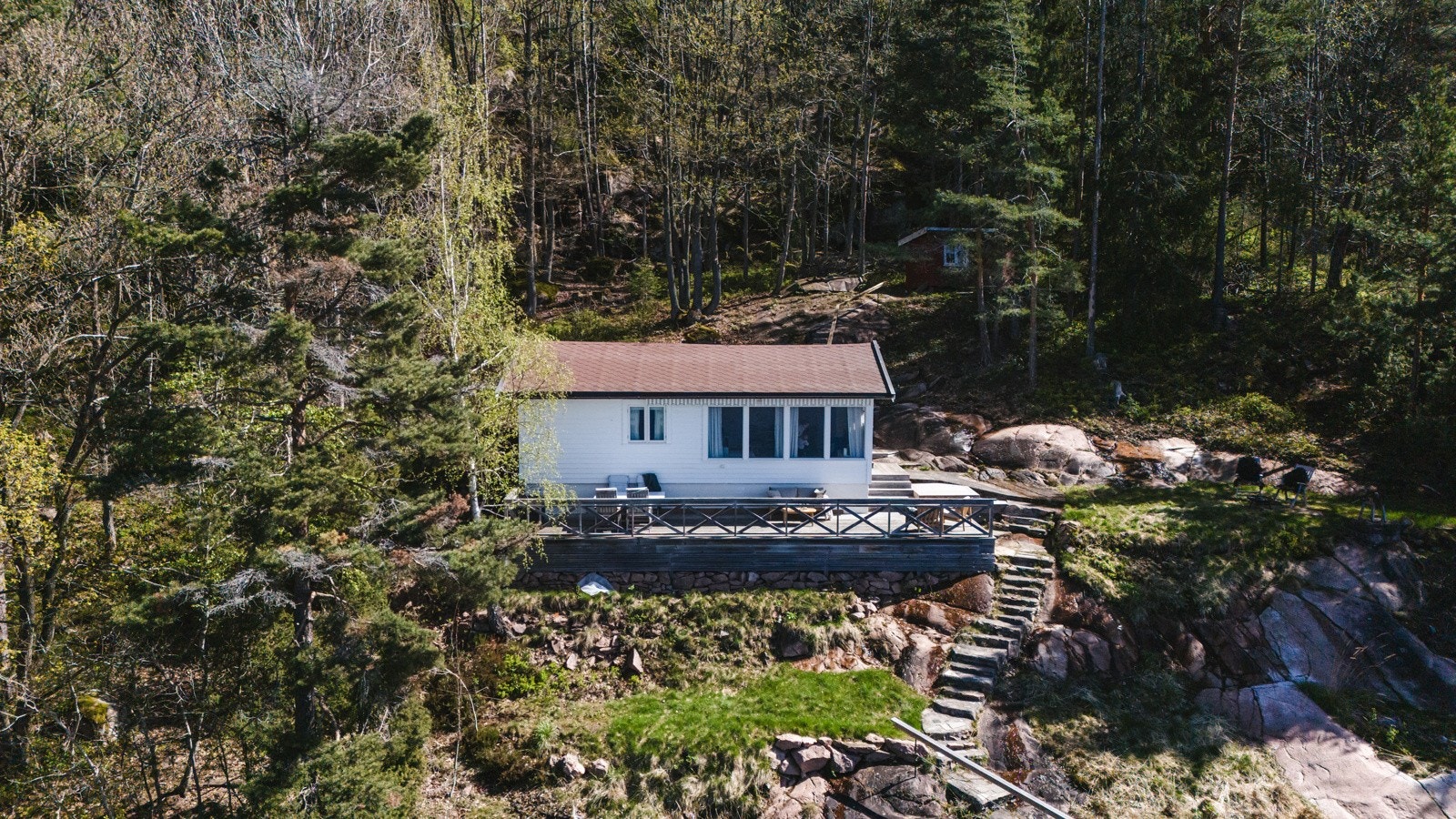 Det er etablert støpt trapp i terrenget mellom brygga og hytta, og anlagt en stor, vestvendt terrasse på ca. 35 kvm utenfor hytta. Galleribilde