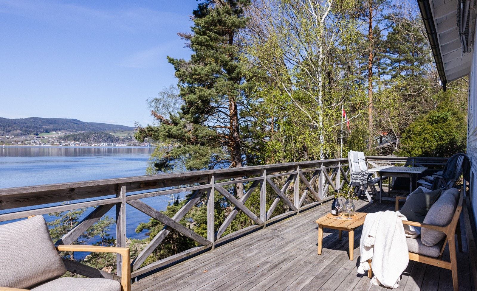 Terrassen har dekke og rekkverk i tre, god plass til møbler og en trapp opp til inngangen på siden av hytta. Galleribilde