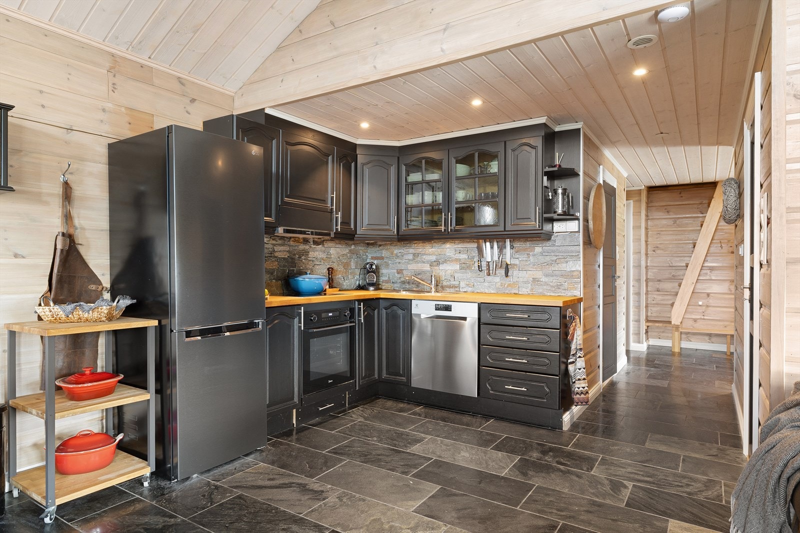 Kjøkkenet har stor innredning i eik med malte, profilerte fronter, heltre benkeplate, fliser over benk. Galleribilde