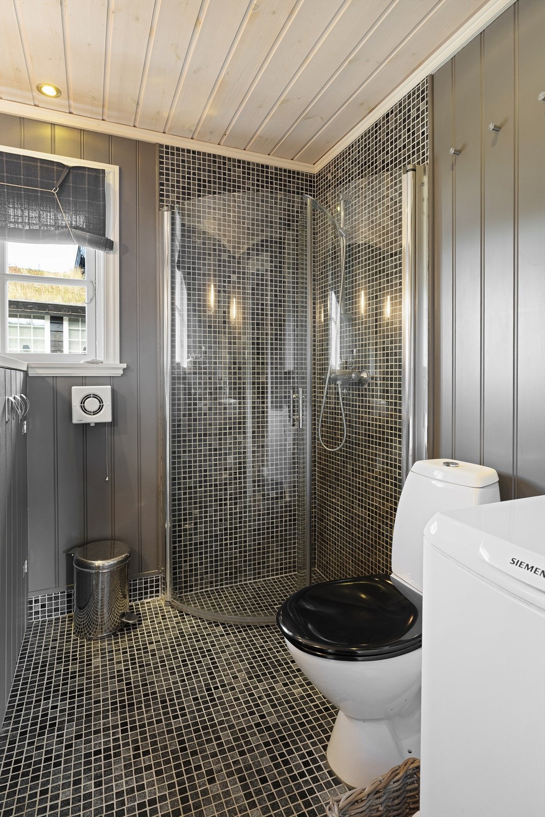 Badet har dusjhjørne, servant med heltre benk, wc og opplegg for vaskemaskin. Galleribilde