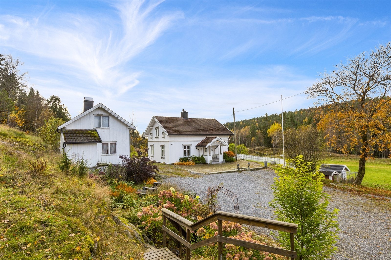 Nydelig tun bestående av stor gruset gårdsplass og opparbeidet hage med prydbusker og beplantninger Galleribilde