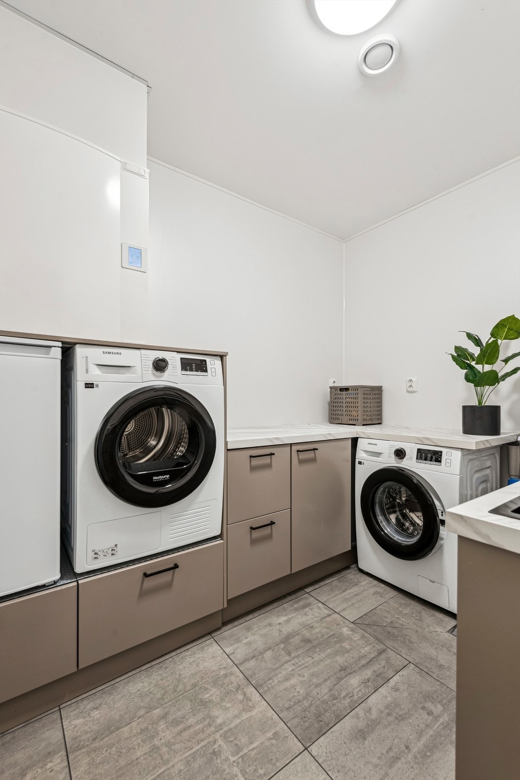 Et separat og praktisk vaskerom med flislagt gulv, varmekabler og opplegg for vaskemaskin. Galleribilde