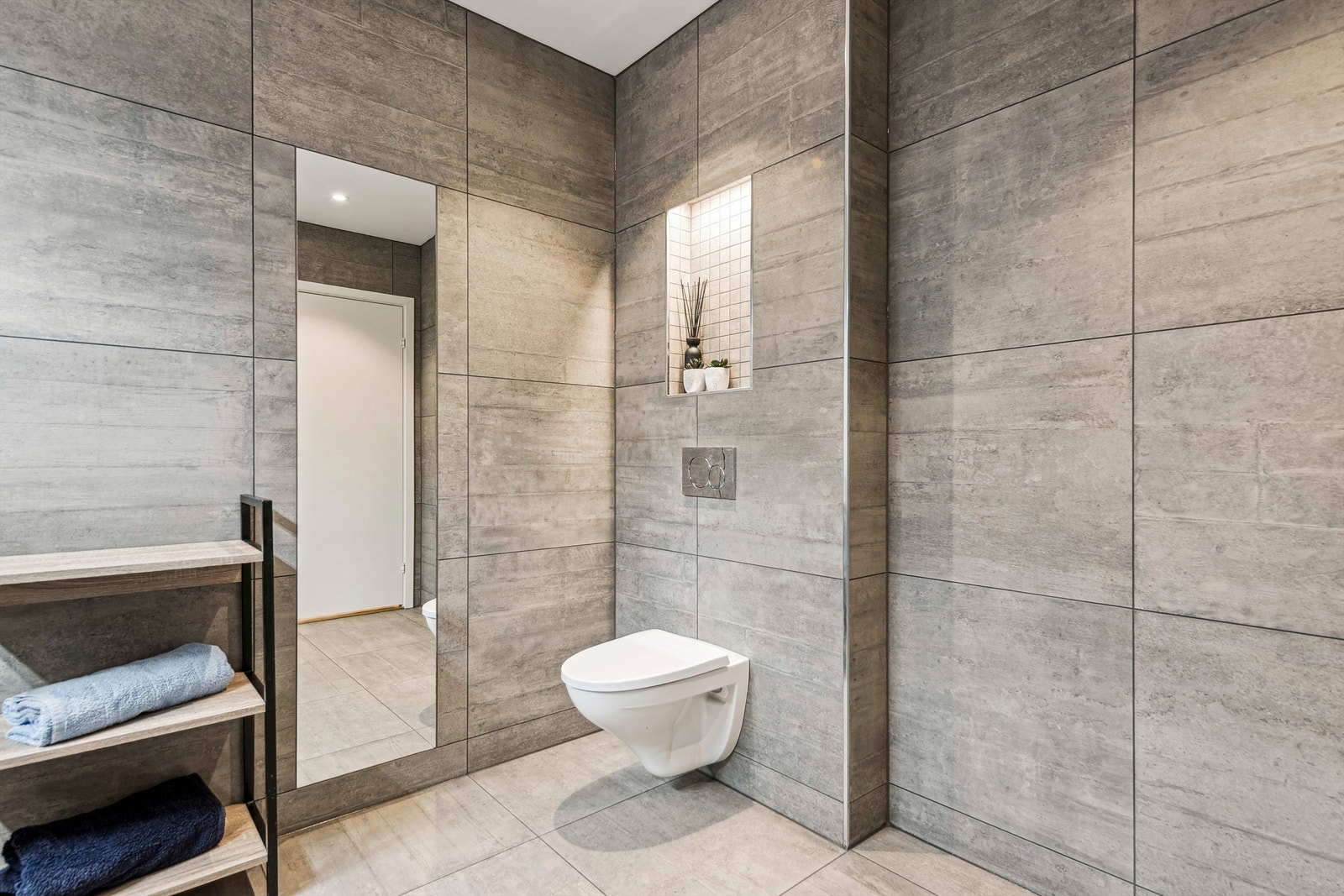 Moderne detaljer som vegghengt toalett og store fliser gir et rent og helhetlig uttrykk. Galleribilde