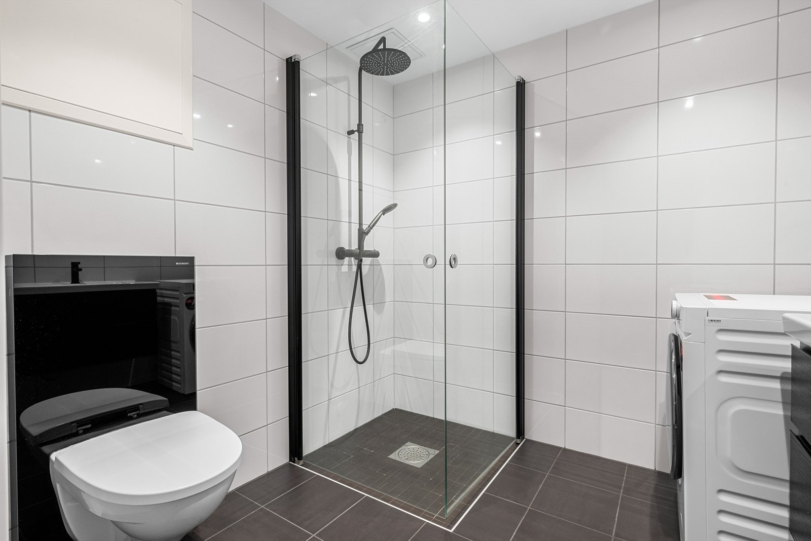 Leiligheten har et pent og innbydende bad med fliser på vegger og gulv. Badet er utstyrt med dusjhjørne, mekanisk avtrekk, veggmontert toalett, rørfordelerskap, stoppeventil, vannmåler, servant i underskap og opplegg for vaskemaskin. Galleribilde