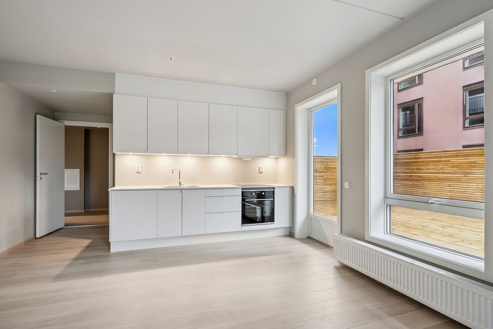 Pent kjøkken med integrerte hvitevarer. Kombiskap rundt hjørnet på venstre side Galleribilde