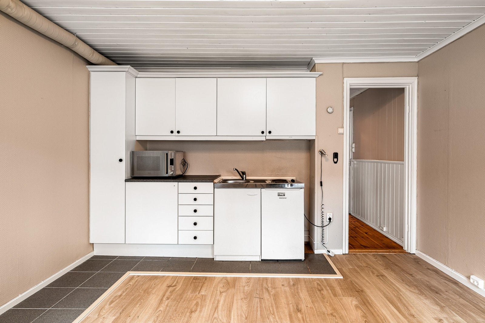 Kjøkkenbenk med kjøleskap, oppvaskkum og 2
kokeplater. Kjøkkenventilator med avtrekk ut Galleribilde