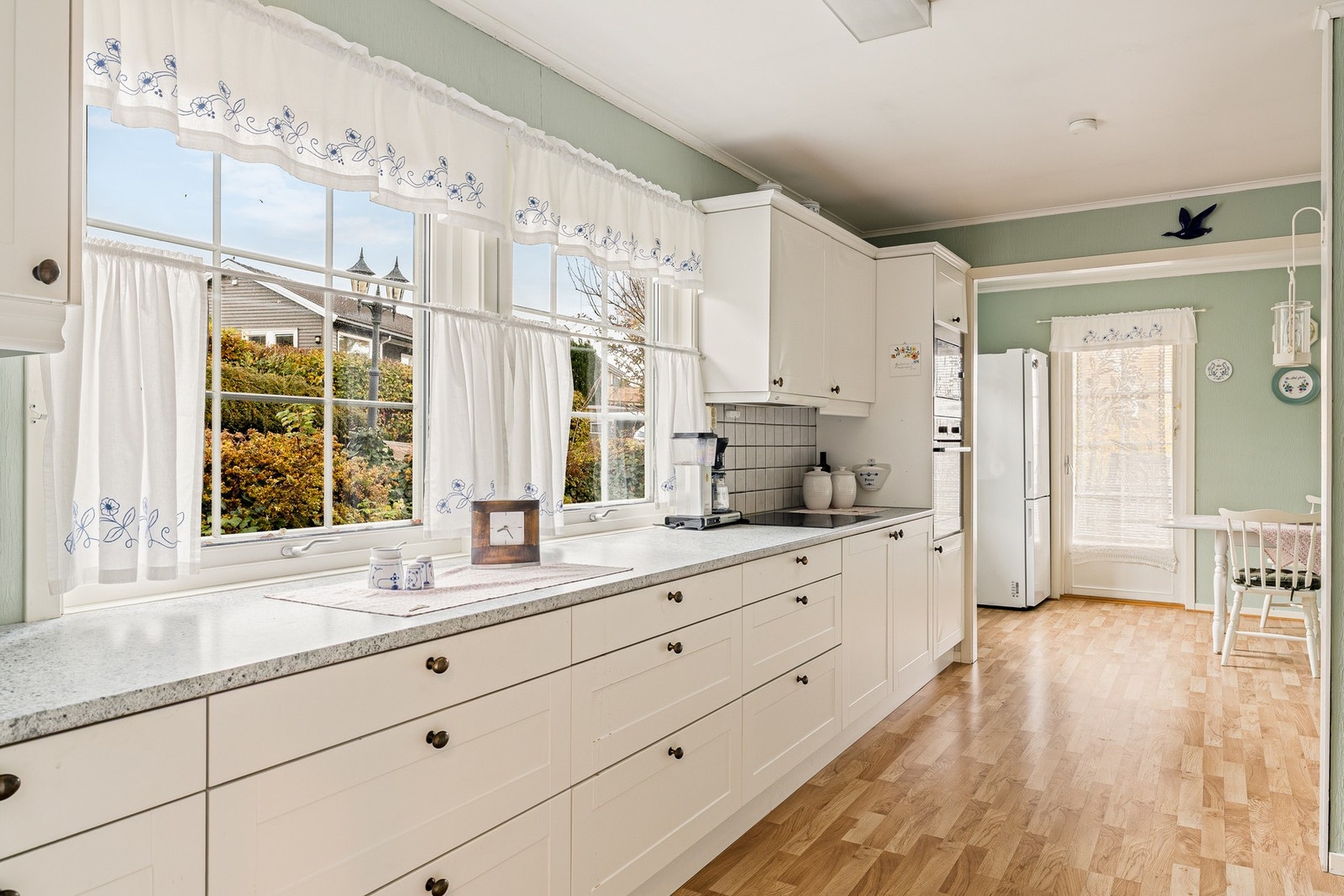 Innredning med profilerte fronter og benkeplate av
laminat med fliser på vegg over kjøkkenbenk Galleribilde