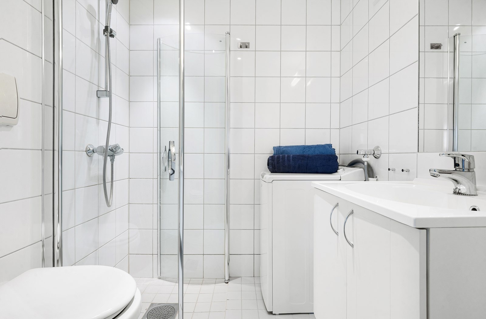 Badet er flislagt og har et praktisk dusjhjørne med innfellbare glassdører. Galleribilde