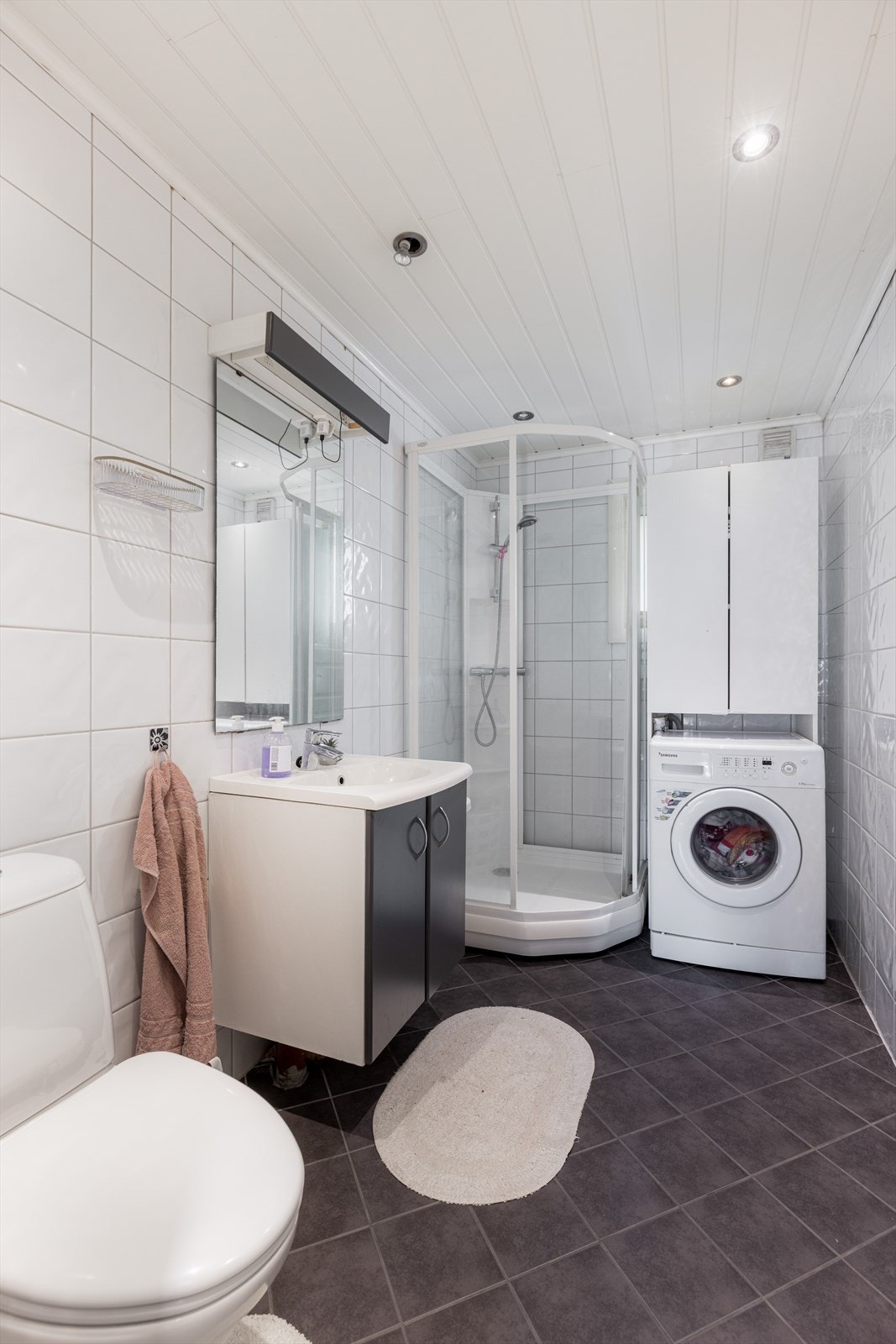 Badet inneholder klosset, dusjkabinett, servant med underskap, speil og opplegg til vaskemaskin. Galleribilde