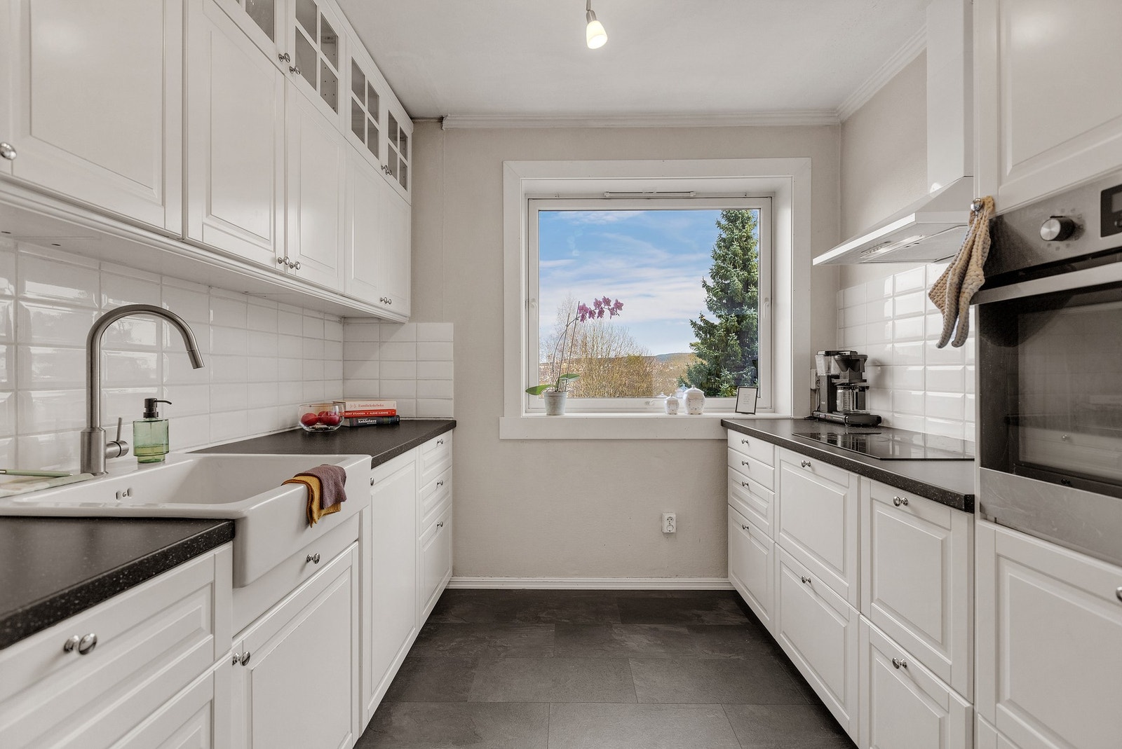 Kjøkkenet er praktisk adskilt fra stuen og fremstår lyst og moderne. Innredningen fra 2014 har profilerte fronter og en laminert benkeplate med nedfelt porselensvask og ett-greps armatur. Galleribilde