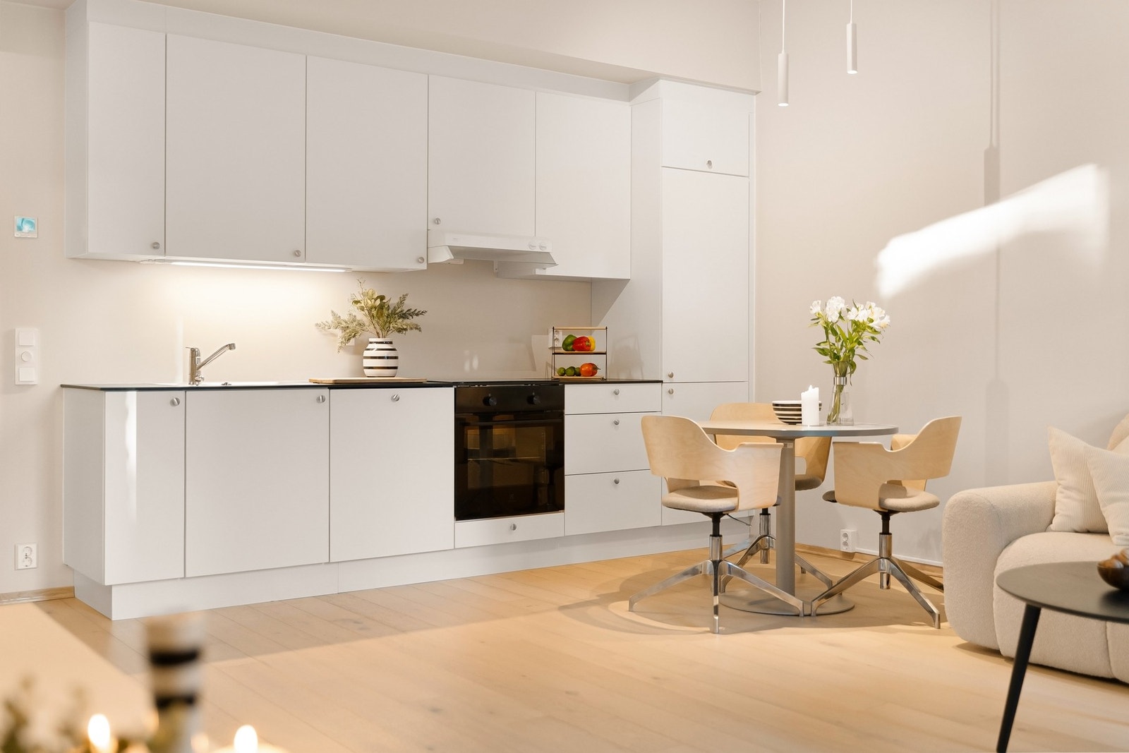 Enkelt og funksjonelt kjøkken med glatte hvite fronter og benkeplate i kompositt Galleribilde