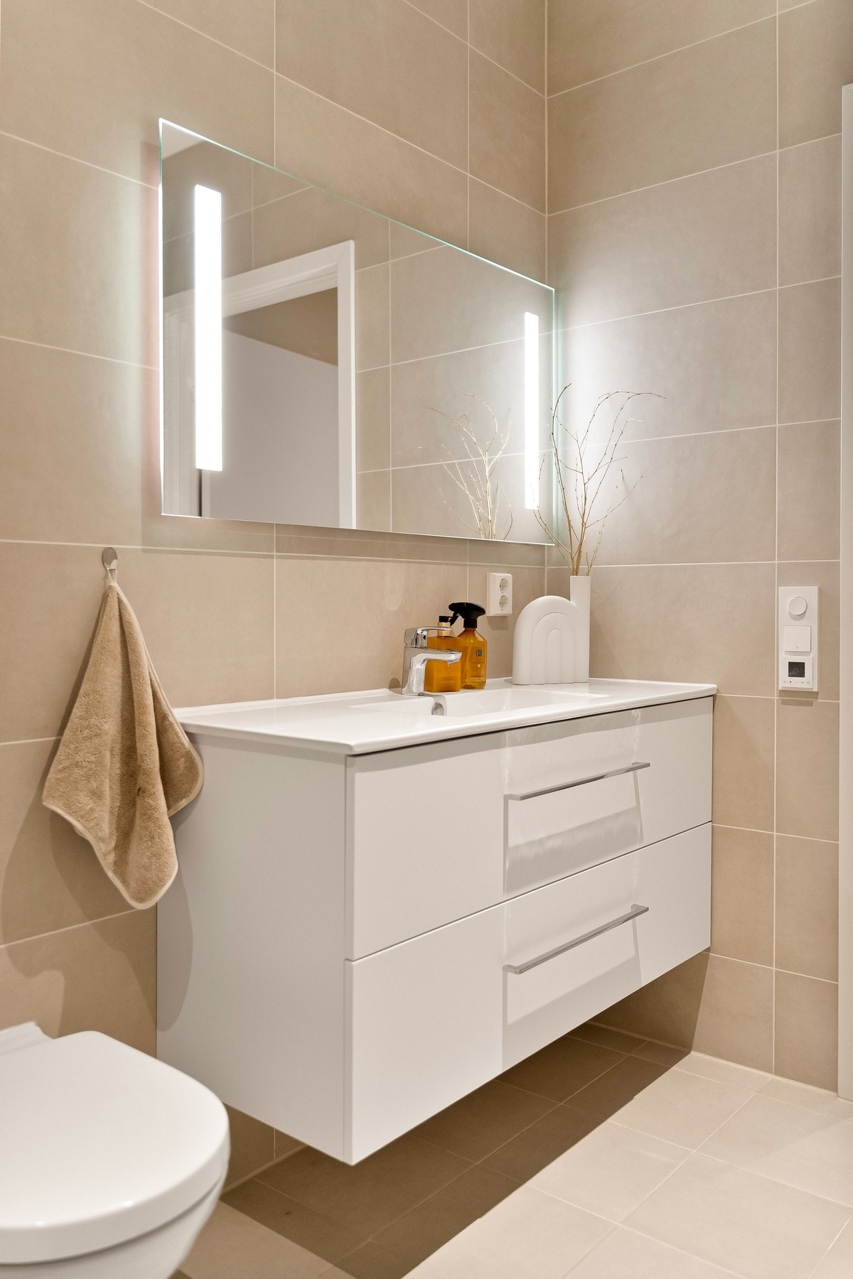 Badet er utstyrt med baderomsinnredning, gulvstående wc, opplegg for vaskemaskin og speil med integrert belysning Galleribilde