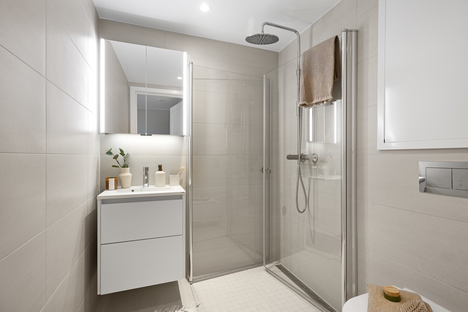 Badet tilknyttet hovedsoverommet er pent utført med lyse fliser på gulv og vegger, innredning fra HTH og regnfallsdusj. Galleribilde