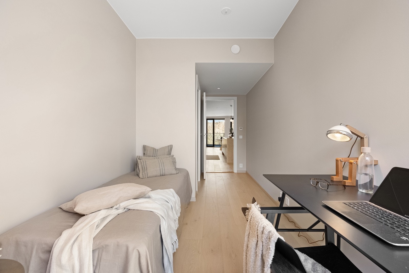 Rommene er malt i lys beige, kombinert med lys, enstavs parkett og listefri himling. Det ene har inngang til bod. Galleribilde