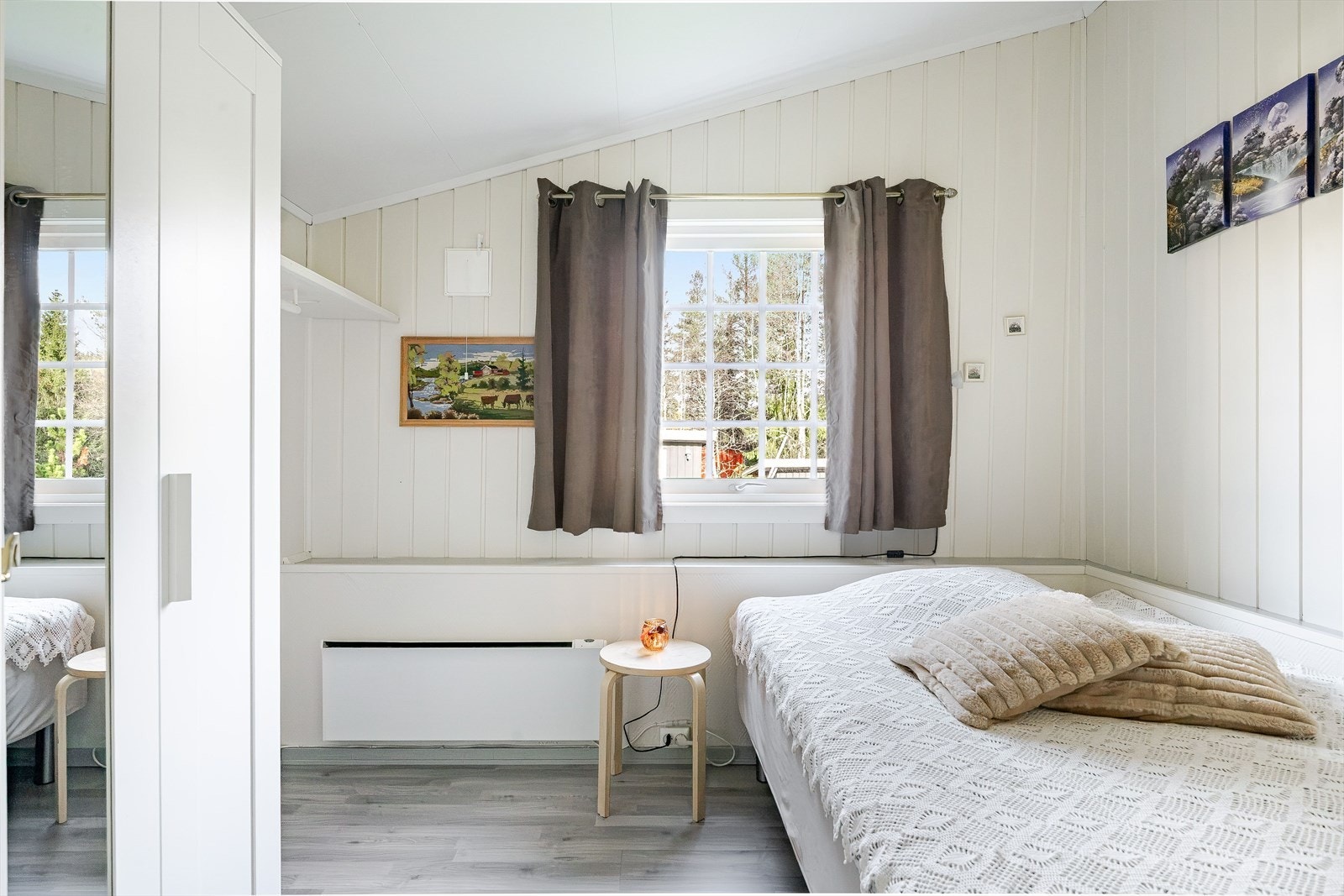 Lyst og trivelig soverom med laminat på gulv og lysmalt panel på veggene. Galleribilde