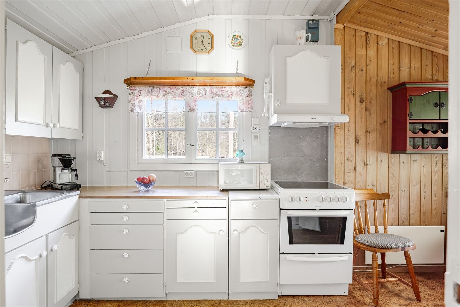 Eldre kjøkkeninnredning med lyse fronter, laminert benkeplate og benkebeslag med nedfelte oppvaskkummer. Galleribilde